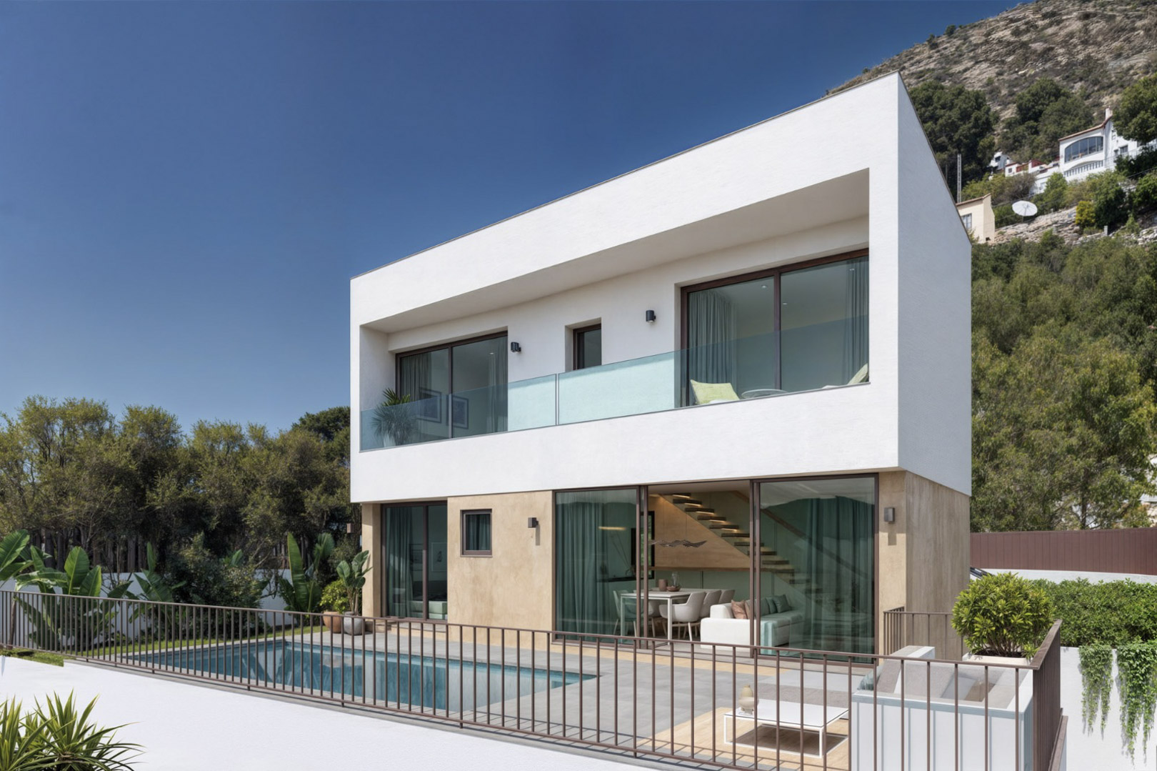 Modern two-story villa featuring a private pool, porcelain terrace, and large glass doors showcasing the open-plan living area and minimalist internal staircase.