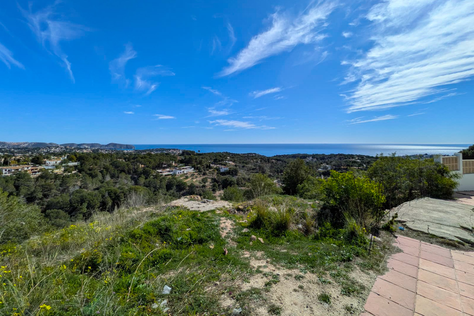 Elevated panoramic view from the plot overlooking the Mediterranean Sea, Cap D'or, and lush pine-covered hills under a bright blue sky.