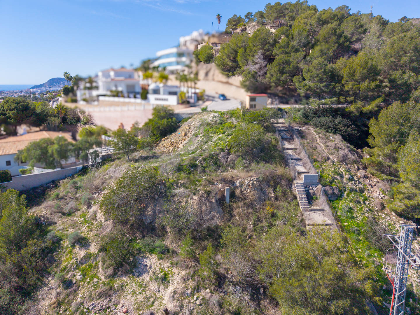 Elevated view of the steep plot in Benissa, featuring a constructed concrete access path and panoramic views of the Mediterranean coastline.