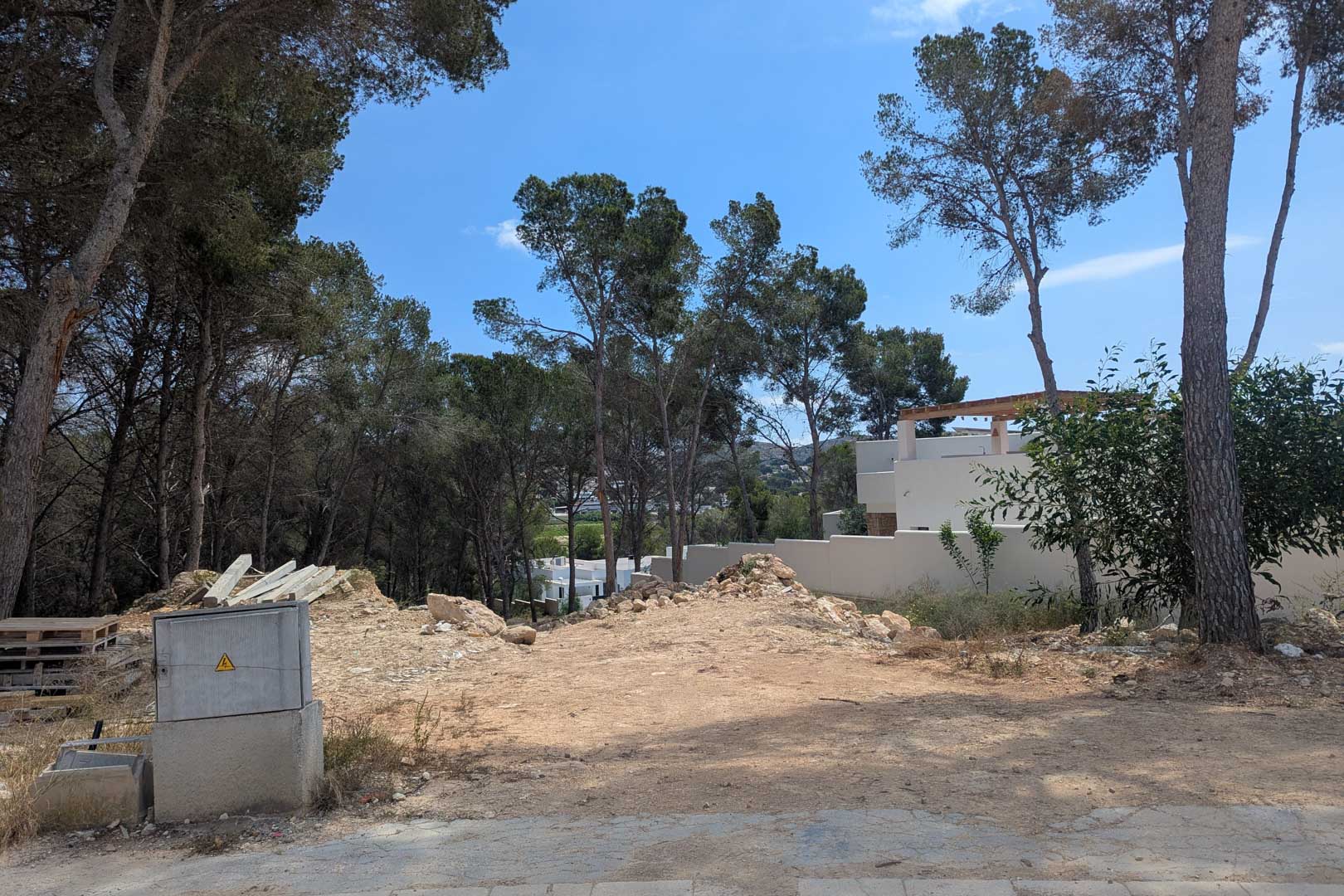 Elevated building plot surrounded by mature pine trees, featuring a prepared ground surface ready for immediate construction.