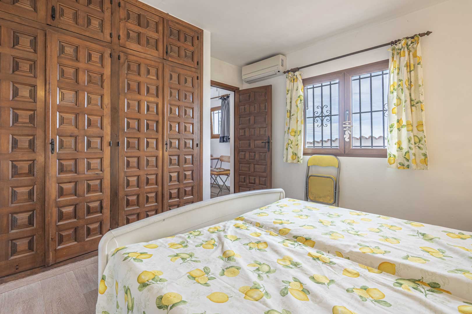 Bedroom featuring a carved wood wardrobe and lemon-print bedding.