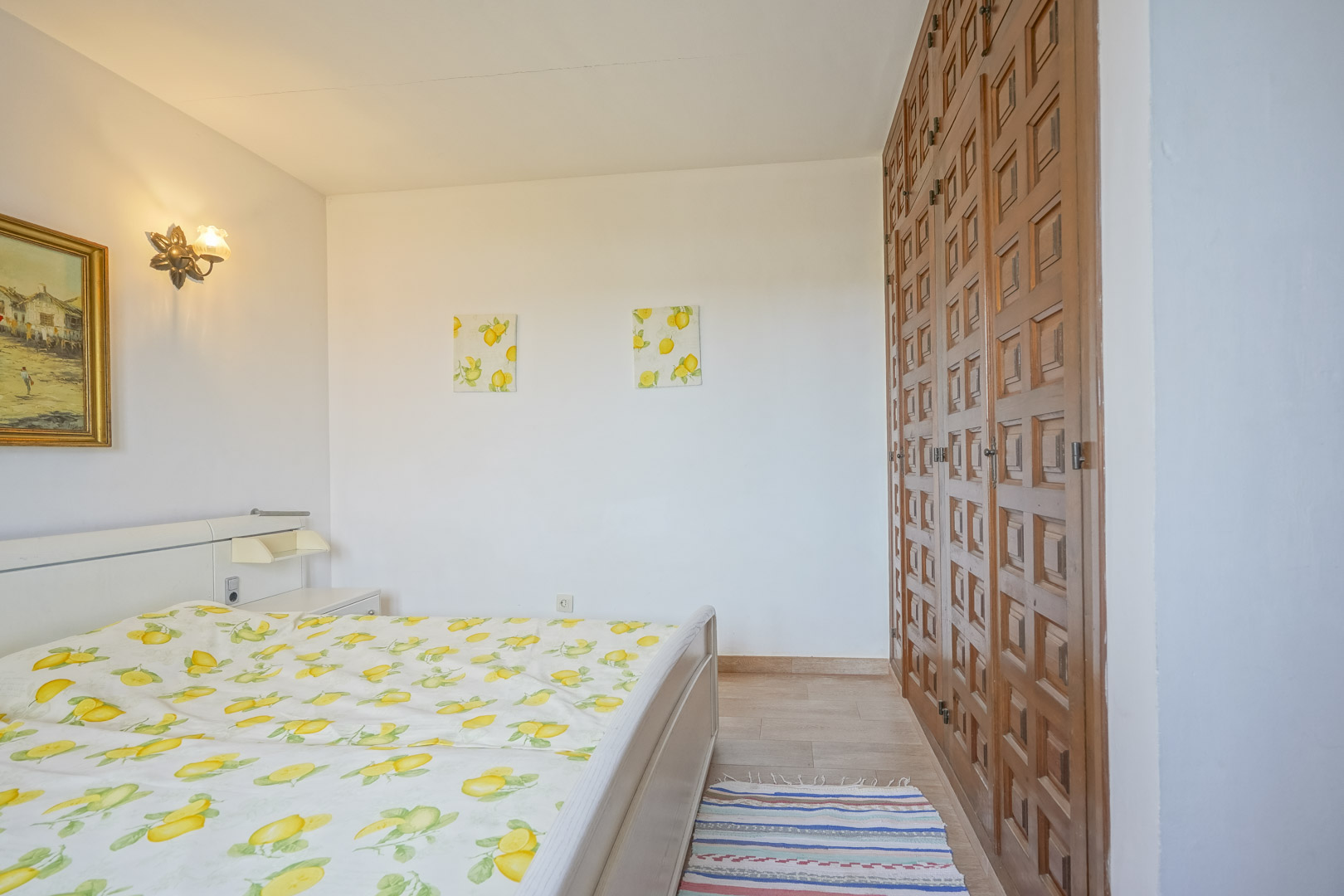 Bright bedroom features a bed, wooden wardrobe, and lemon-themed decor.