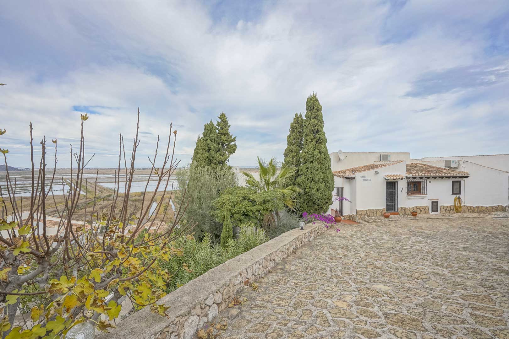 Exterior view of the villa featuring a stone-paved driveway, garden, and panoramic views of the nature reserve.