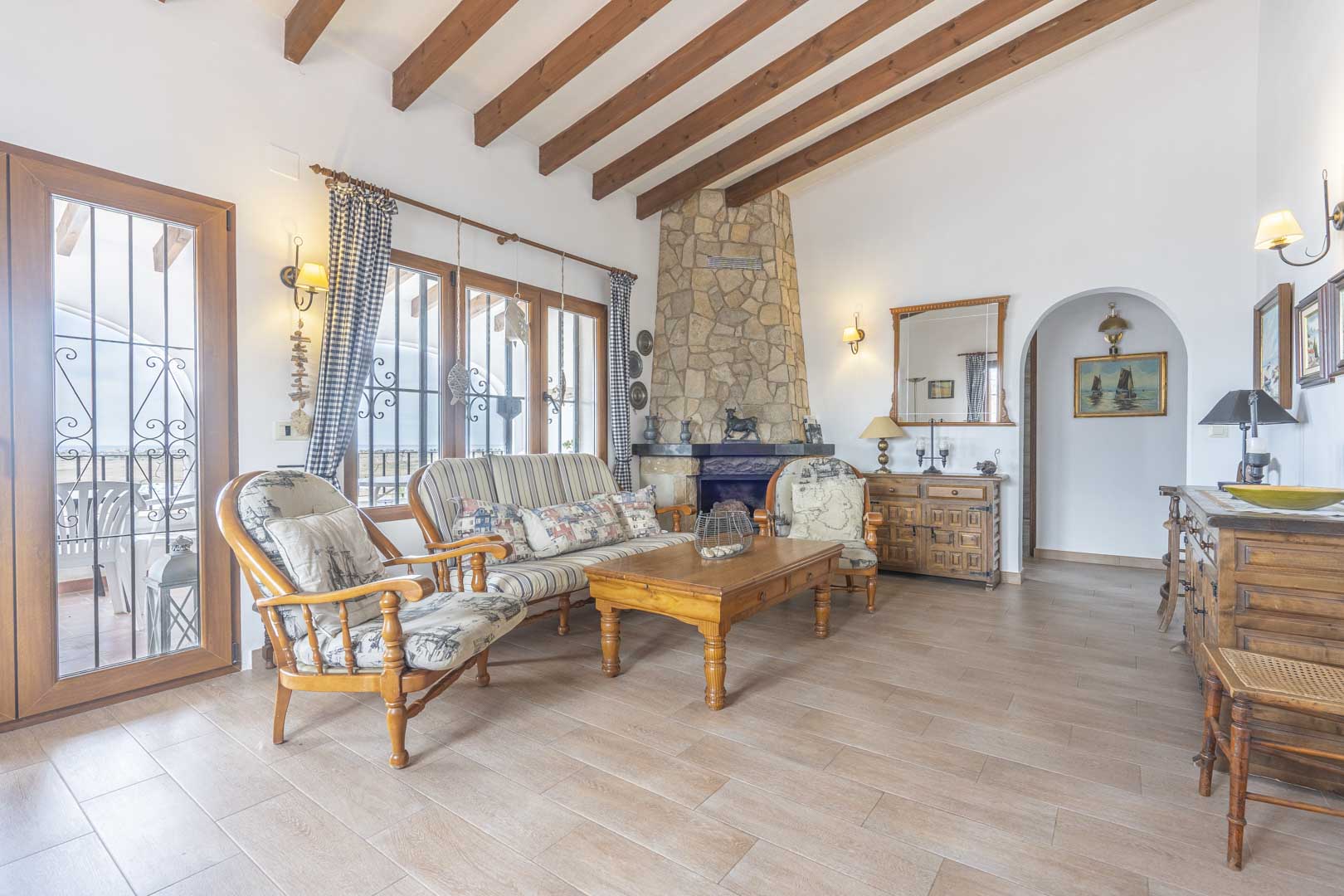 Living room featuring a stone fireplace, wood beam ceiling, and rustic-style furniture.