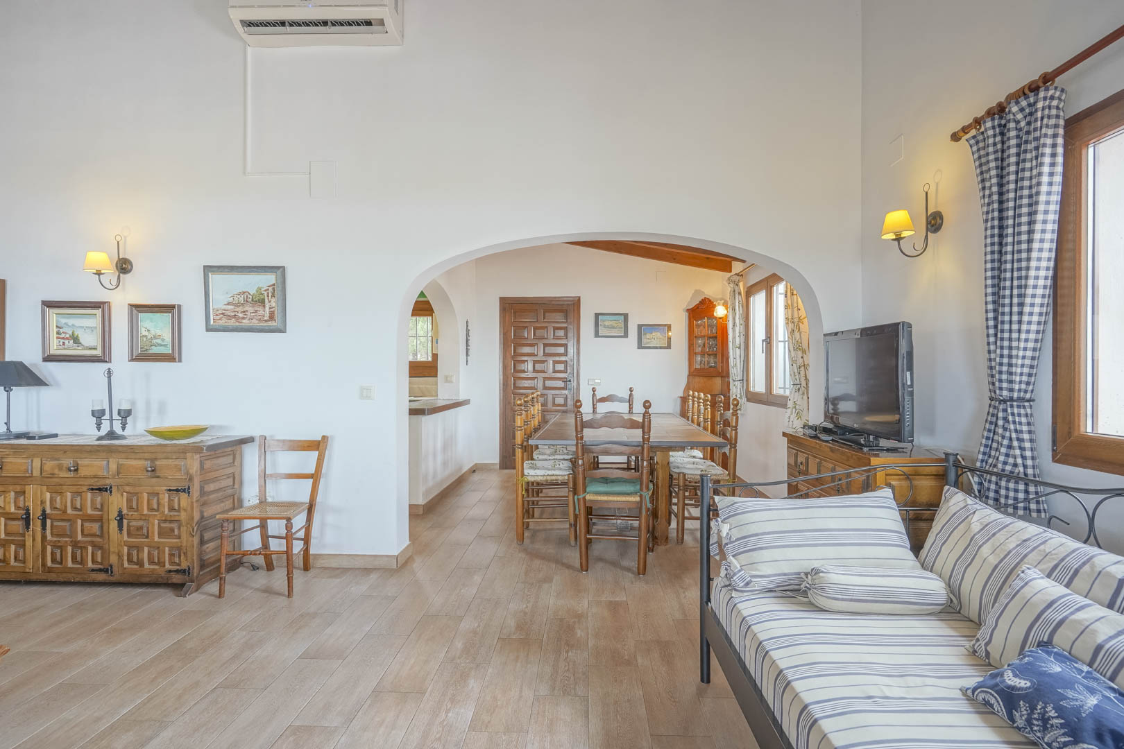 Living room featuring ceramic floors, arched openings to the dining area, and rustic wood furniture.