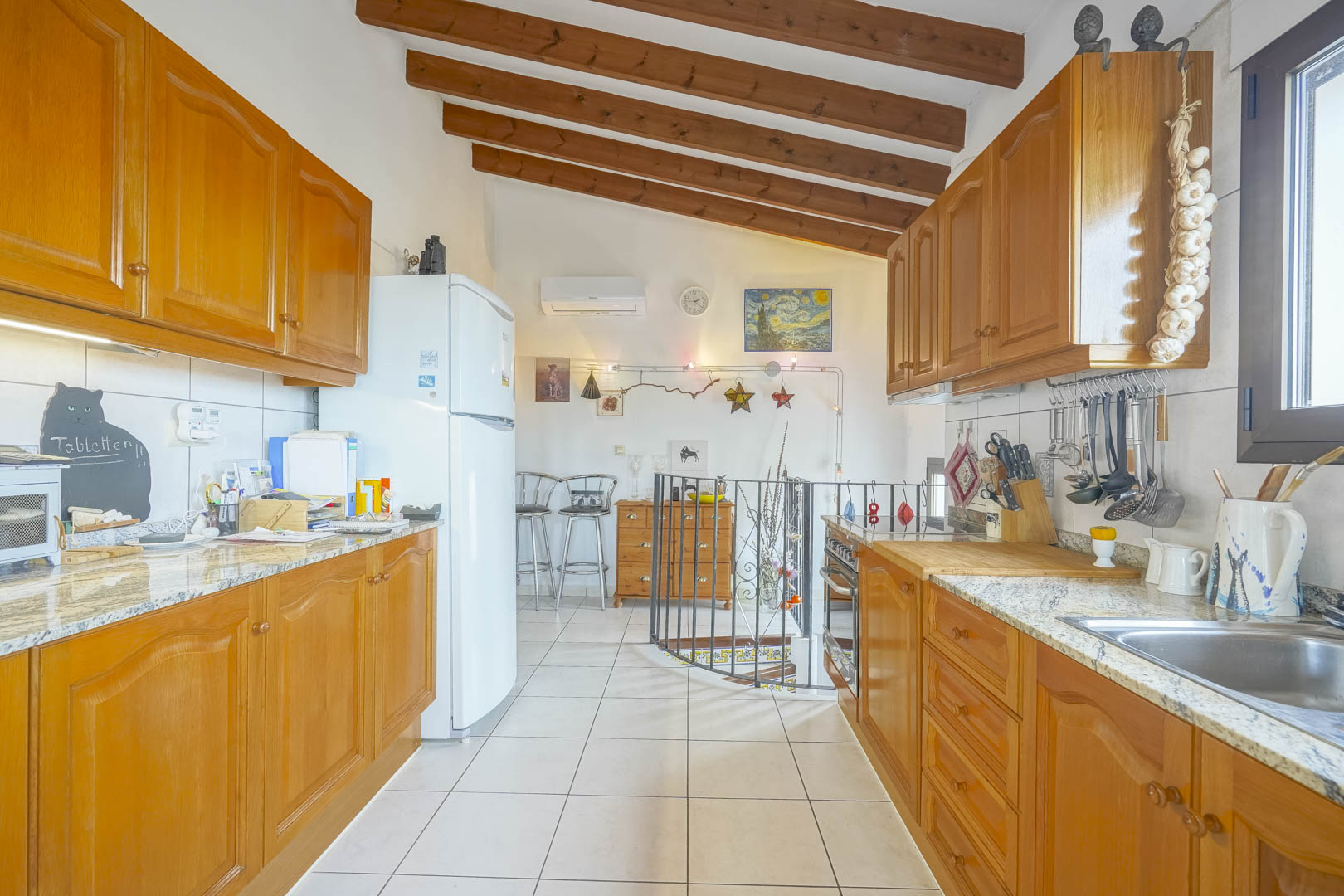 Open kitchen featuring wood beams, wood cabinetry, and granite countertops.