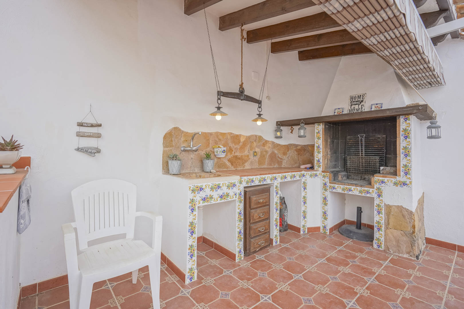 Outdoor barbecue with stone countertop and decorative tiles in a Spanish-style villa.