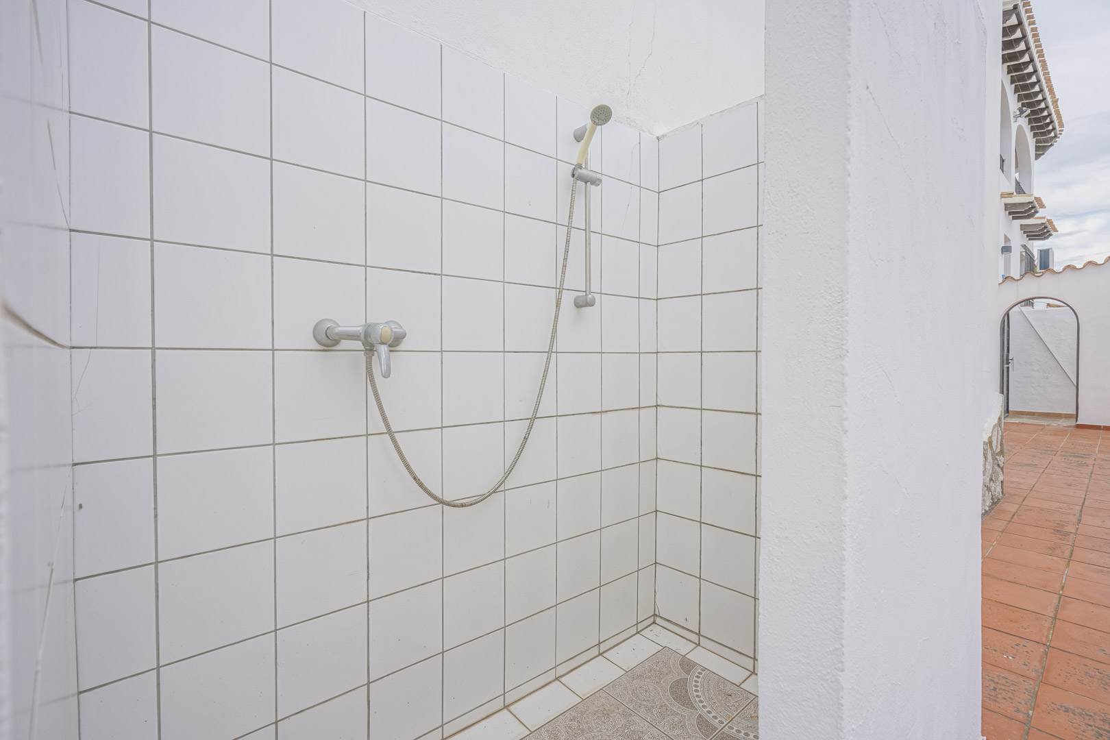 Outdoor shower with white tiles and decorative floor in Monte Pego villa.