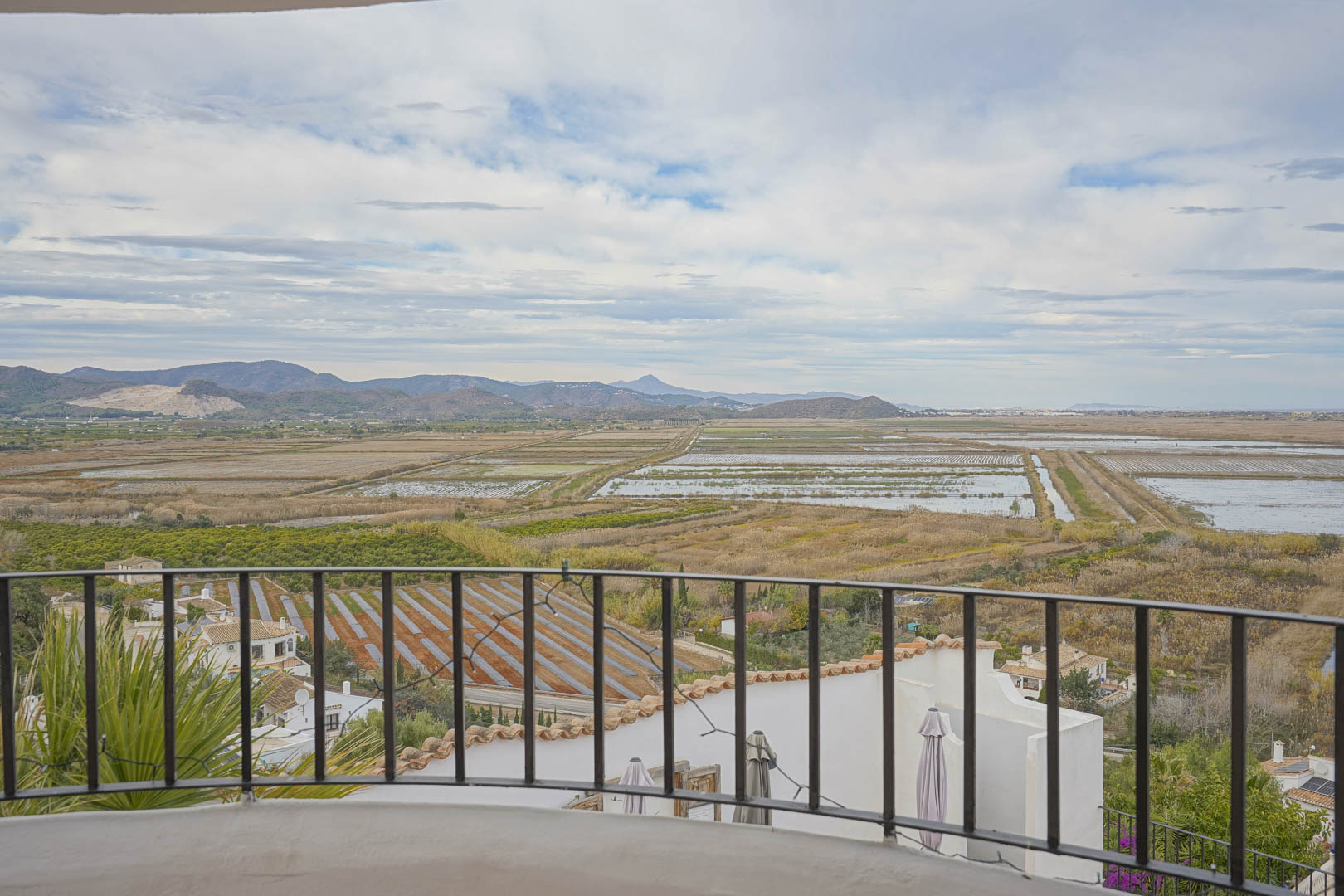 Panoramic views from the terrace with wrought iron railing over the rice paddies and mountain landscape.