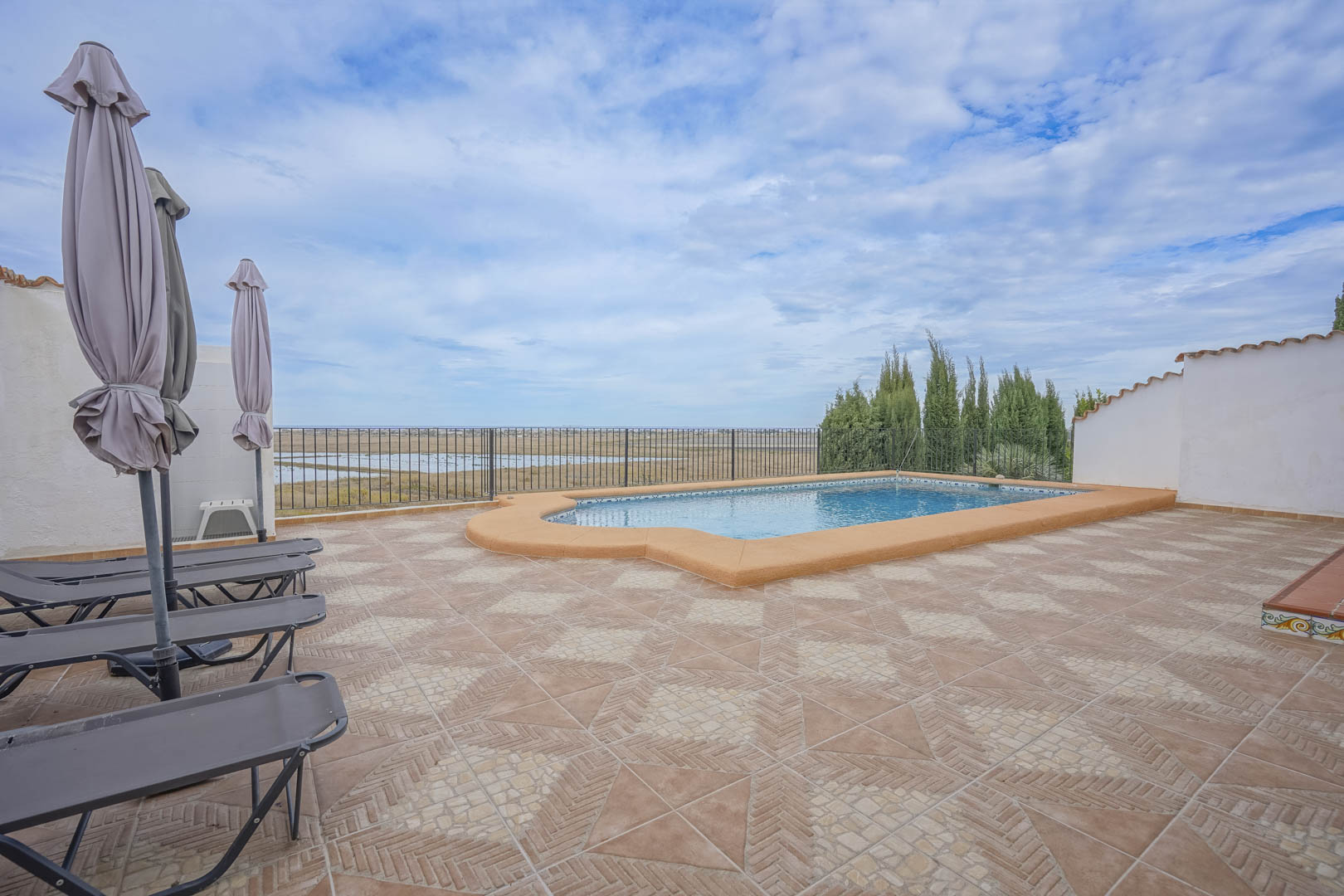 Pool view featuring lounge chairs and closed umbrellas, overlooking the nature reserve.