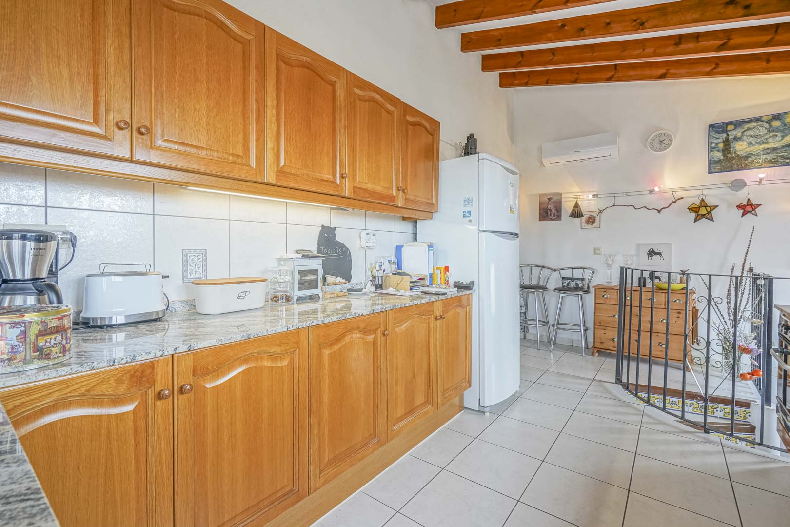Renovated open kitchen featuring wood cabinetry, granite countertops, and modern appliances.