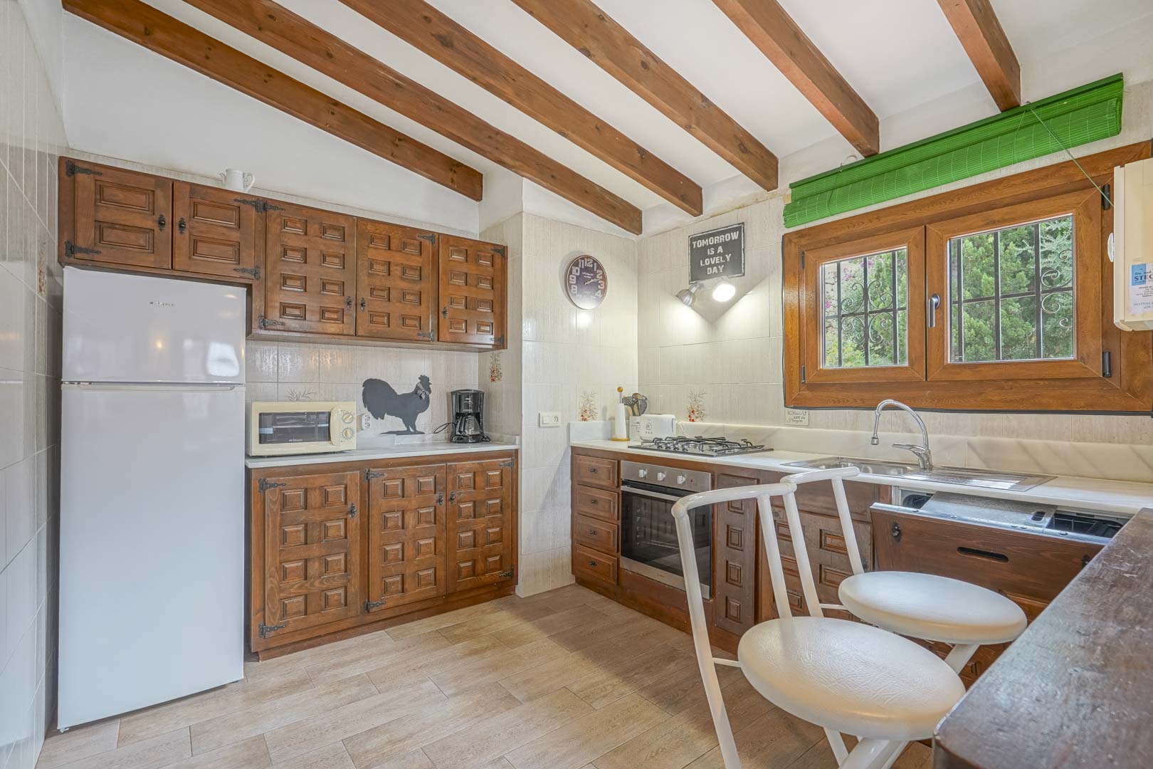 Rustic kitchen featuring wood beam ceilings, carved wood cabinets, and modern appliances.