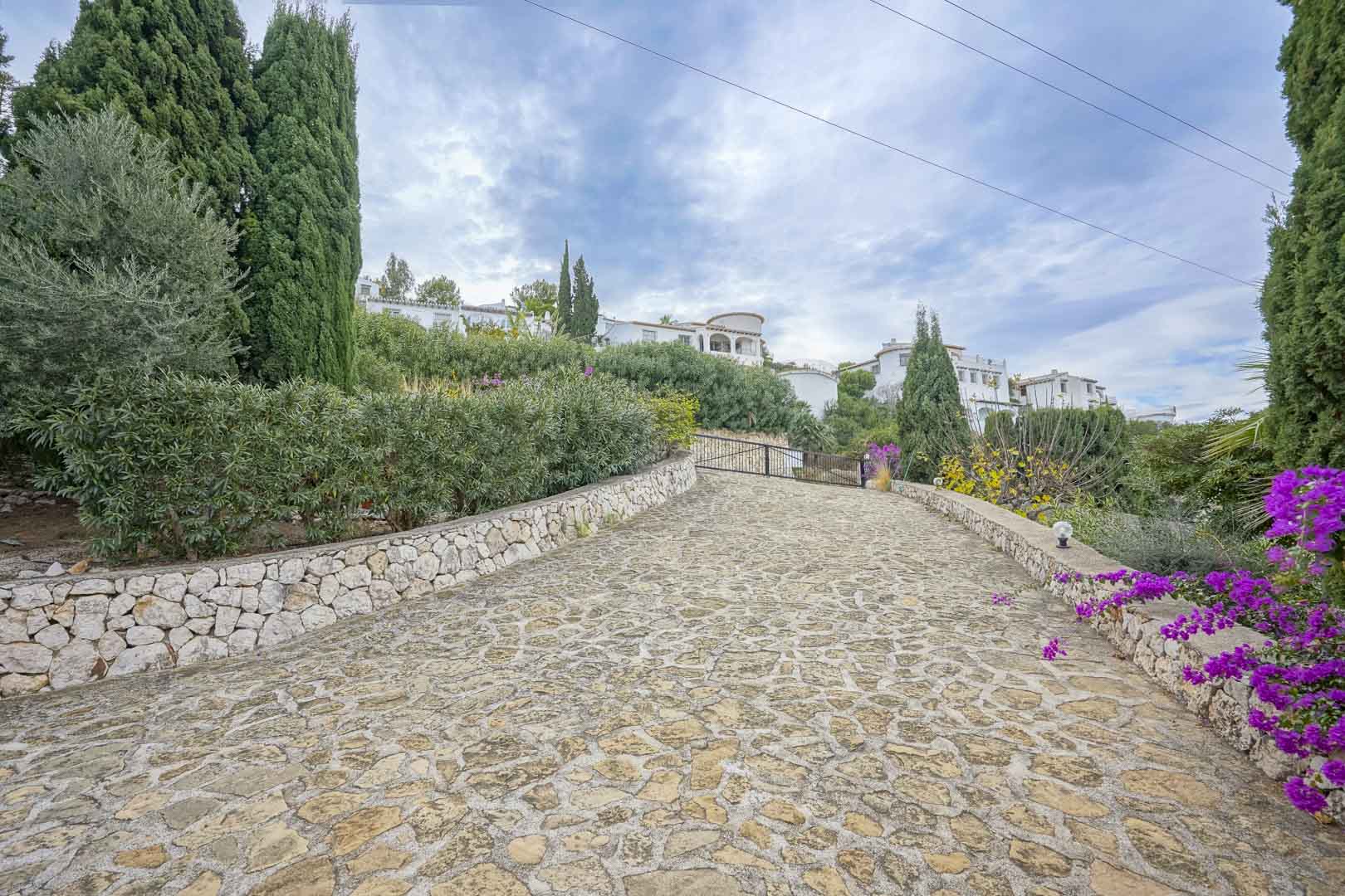 Stone driveway leading to the villa, lined with gardens and greenery.