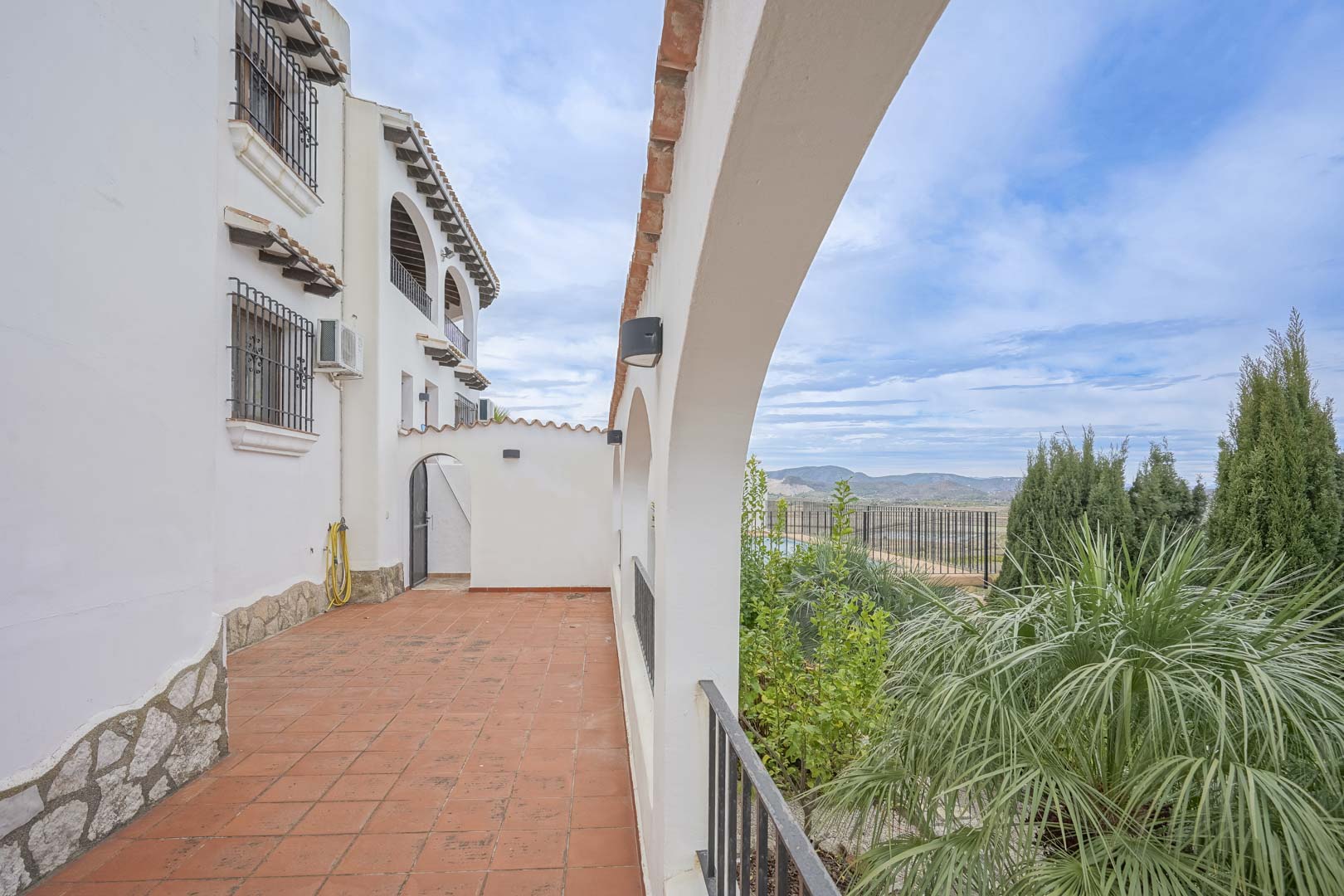 Terracotta-tiled terrace with white arches and panoramic Monte Pego views.