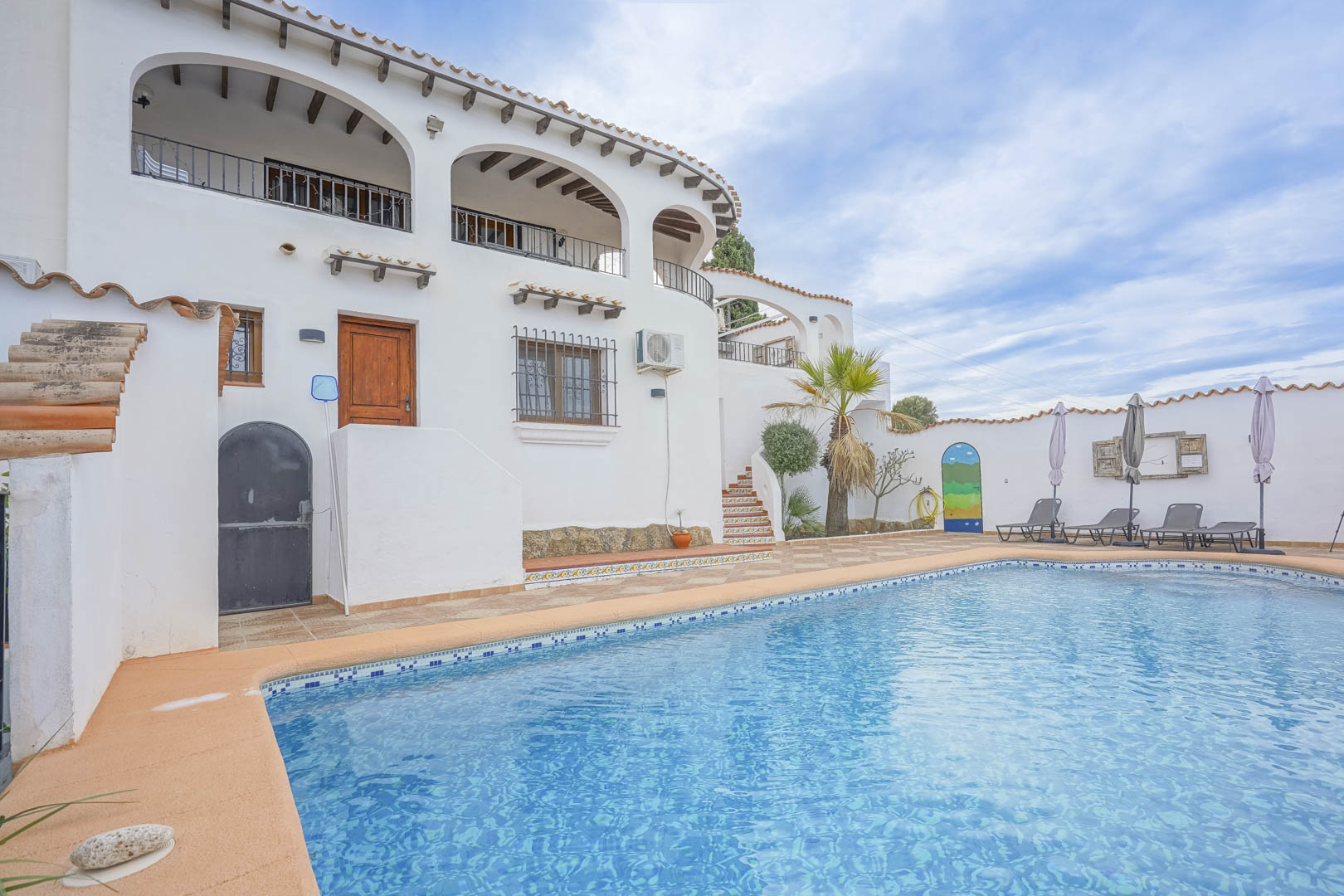View of the blue-tiled pool and the white facade of the Castilian-style villa in Monte Pego.