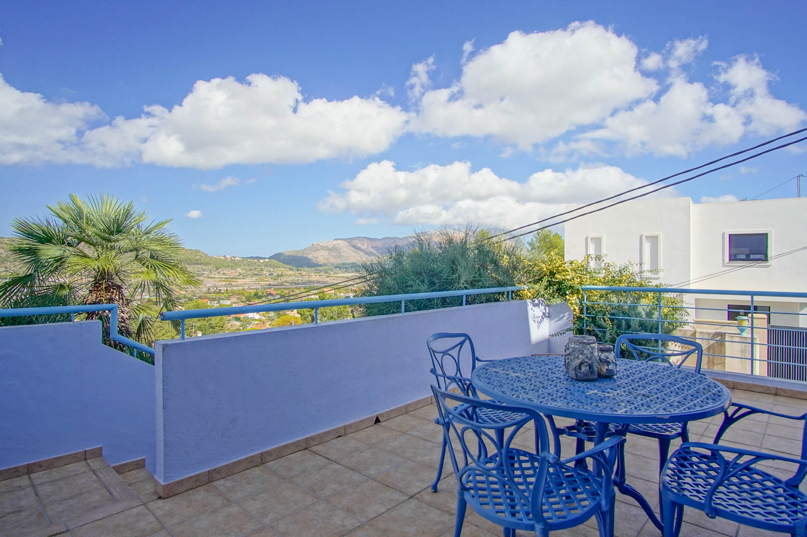 Elevated terrace featuring blue wrought iron furniture, tiled flooring, and panoramic views of the valley and mountains in Pedreguer.