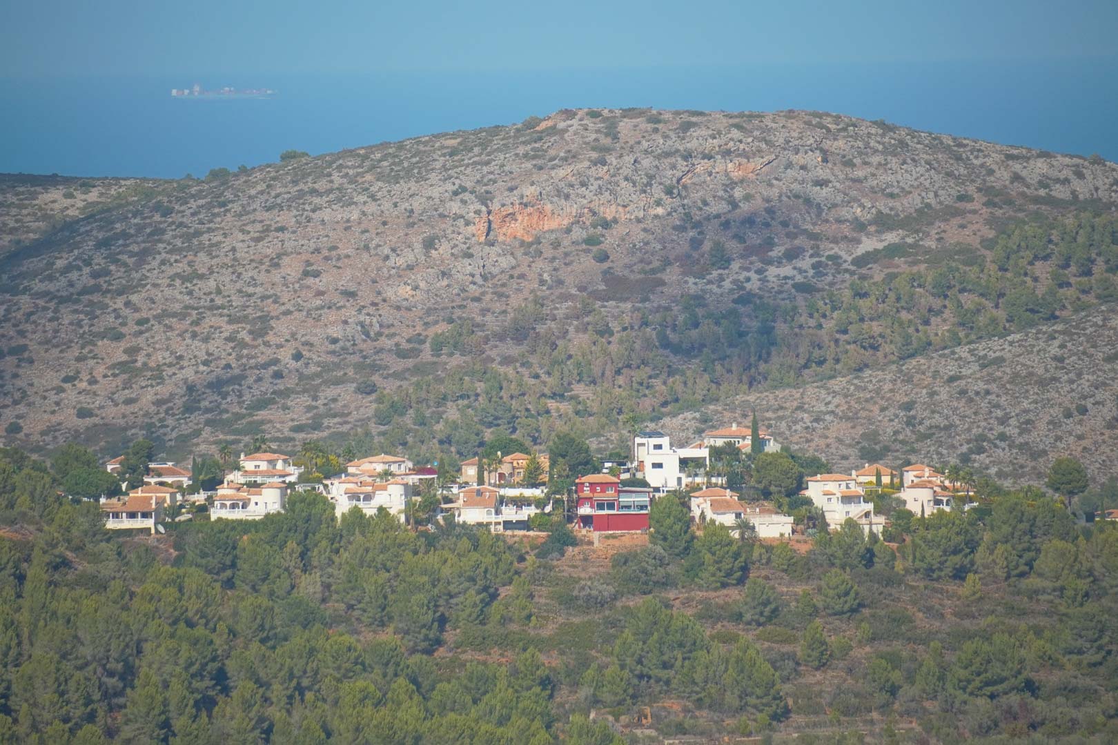 Panoramic view from the property overlooking the hillside urbanization, dense pine forests, and the Mediterranean Sea on the horizon.