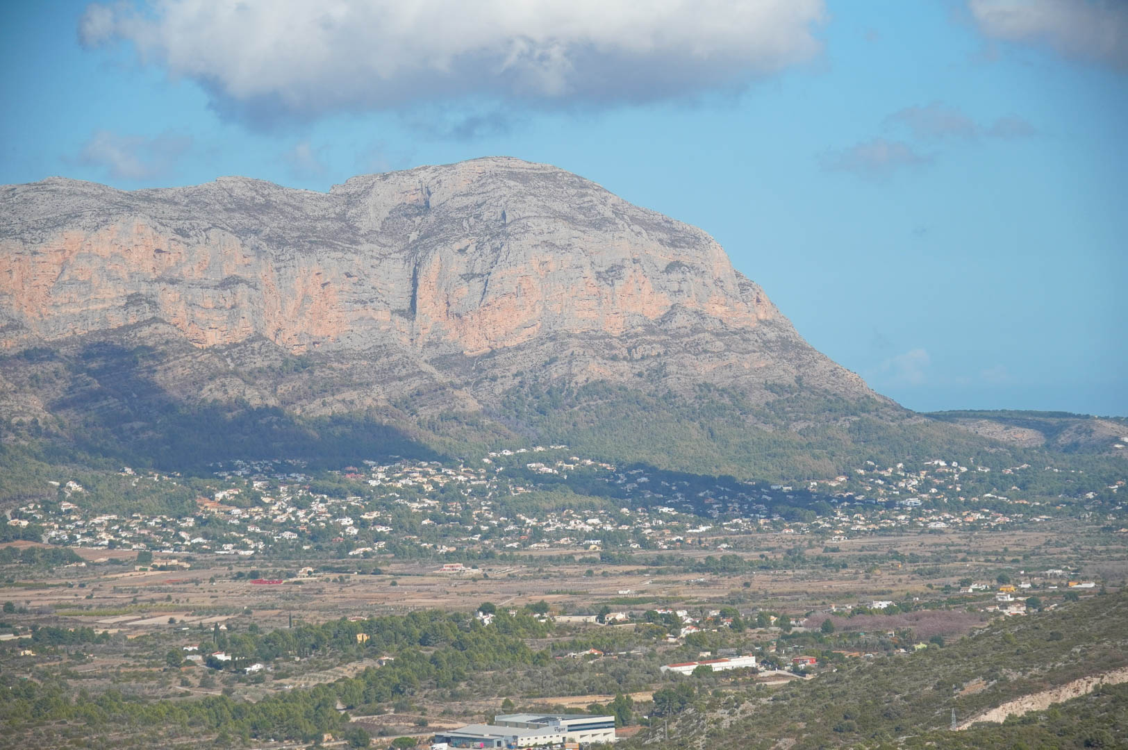 Panoramic view of the Montgó mountain range and the verdant valley, showcasing the natural landscape and residential developments from an elevated vantage point.