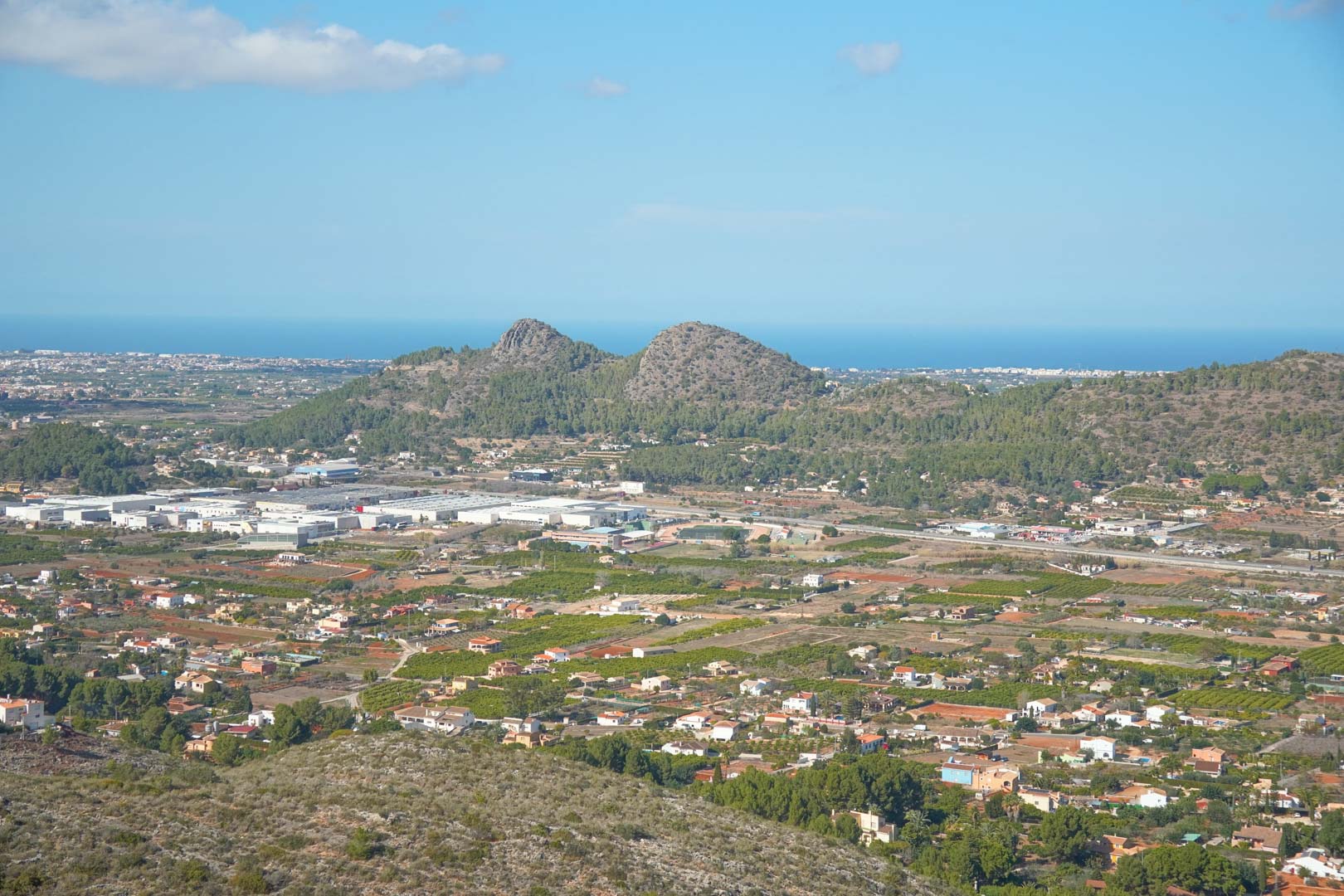 Panoramic views from the property overlooking the Pedreguer valley, featuring surrounding mountains and the Mediterranean Sea on the horizon under a clear sky.