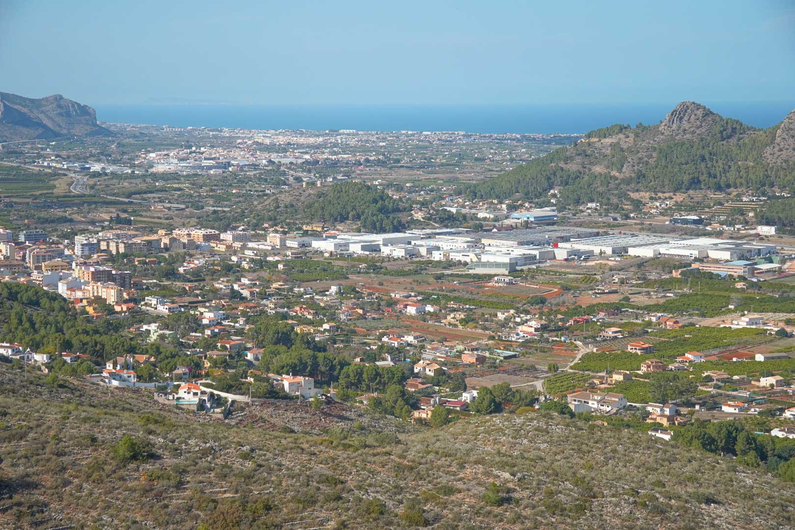 Panoramic views from the property overlooking the Pedreguer valley, featuring the urban landscape and the Mediterranean Sea on the horizon under a clear sky.