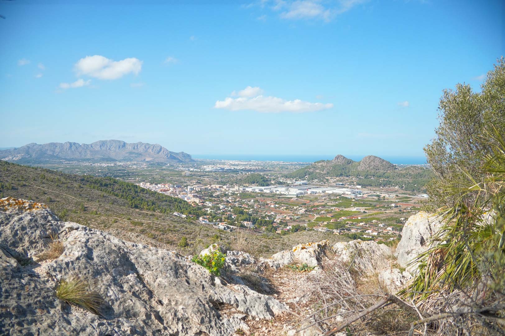 Panoramic views from the property overlooking the Pedreguer valley, surrounding mountains, and the Mediterranean Sea on the horizon under a clear sky.