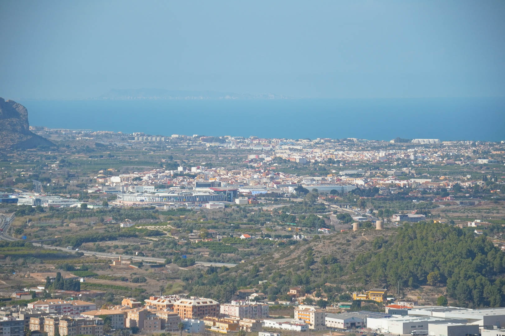 Panoramic views from the property overlooking the valley, urban areas, and the Mediterranean Sea on the horizon under a clear sky.