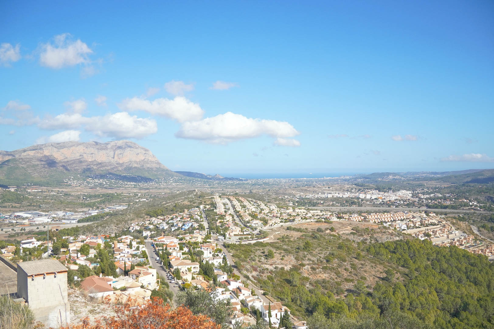 Panoramic views of the Pedreguer valley and the Montgó massif, with the Mediterranean Sea visible on the horizon under a clear blue sky.