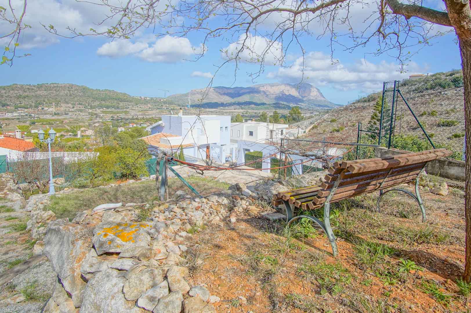 Private viewpoint featuring a wooden bench and natural stone wall, overlooking the valley with expansive mountain views and clear, bright skies.