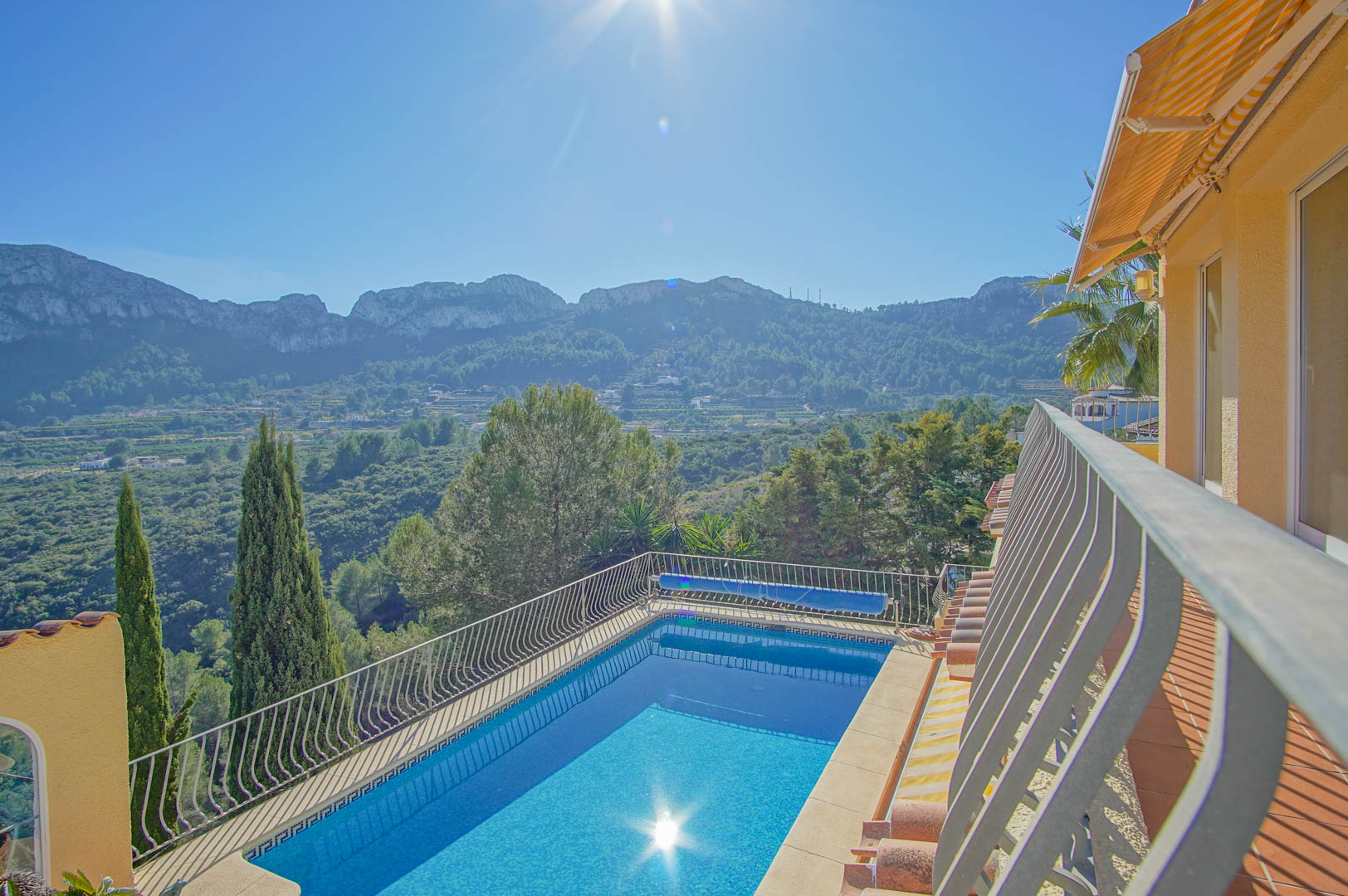 Elevated view of the rectangular swimming pool featuring a metal safety railing and panoramic vistas of the surrounding green valley and mountains.