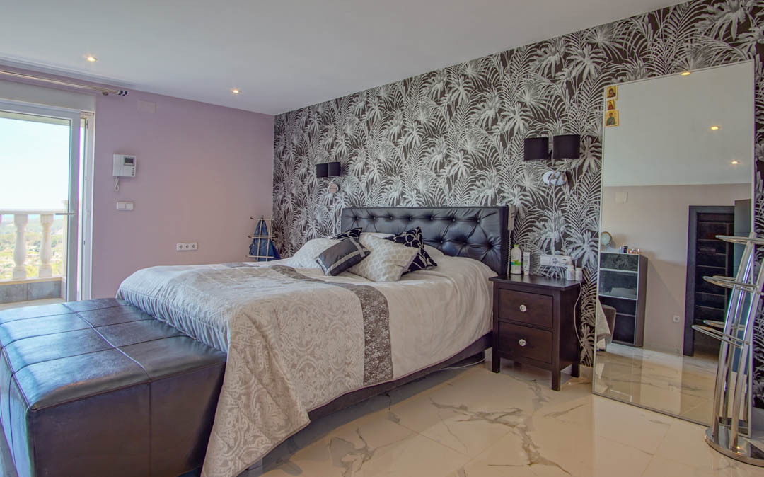 Bedroom featuring marble-effect flooring, a tropical leaf accent wall, tufted leather headboard, and direct access to a private balcony.