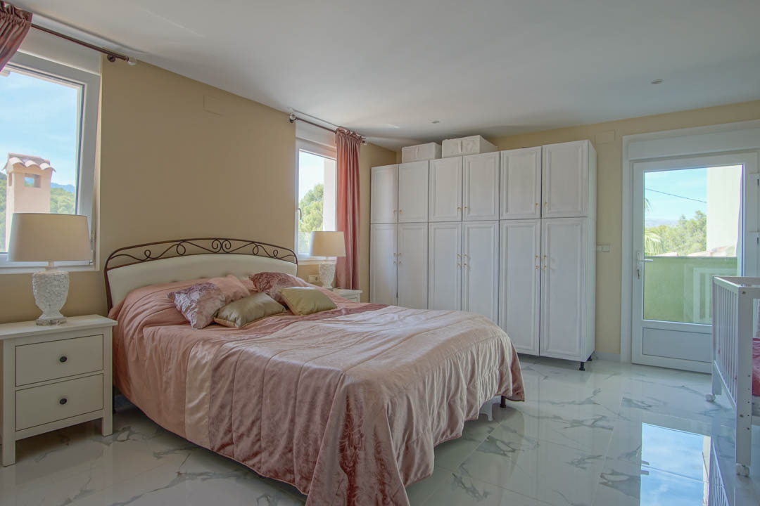 Bedroom featuring marble-effect porcelain flooring, extensive white wardrobes, and a glass door leading to a balcony with mountain views.