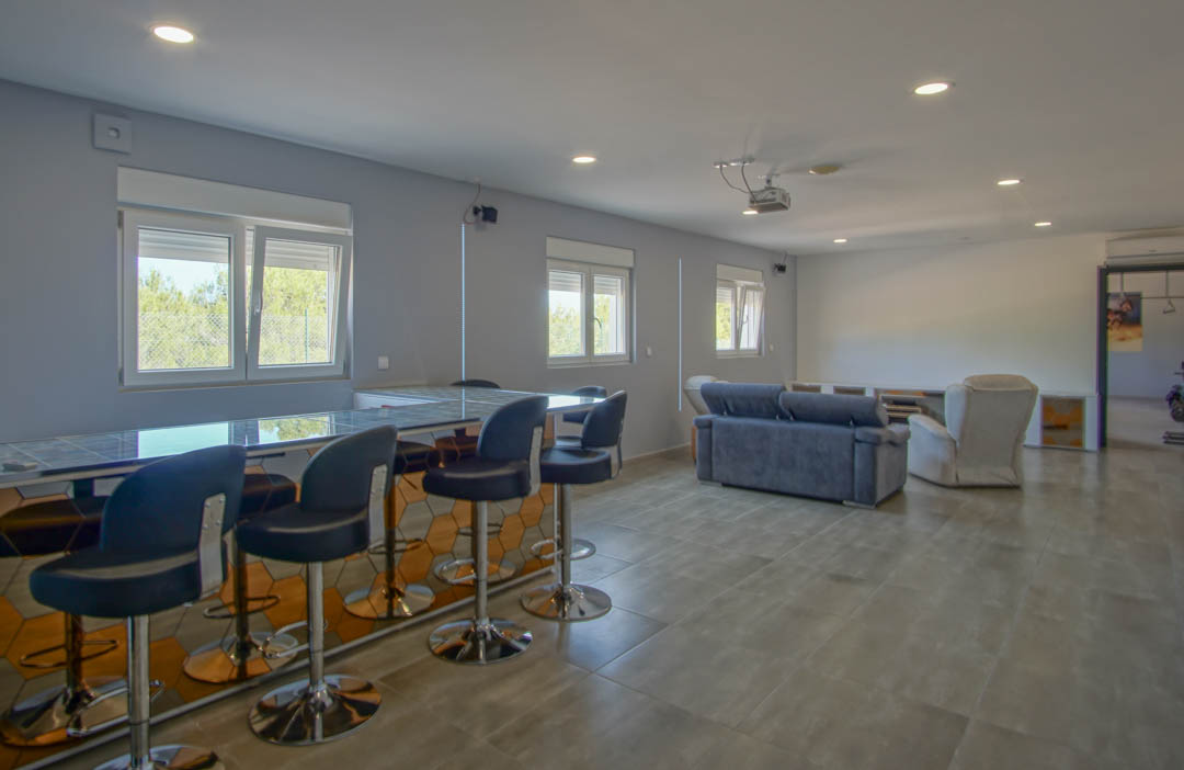 Ground floor entertainment room featuring a private bar with hexagonal mirrored detailing and a cinema area with ceiling-mounted projector.