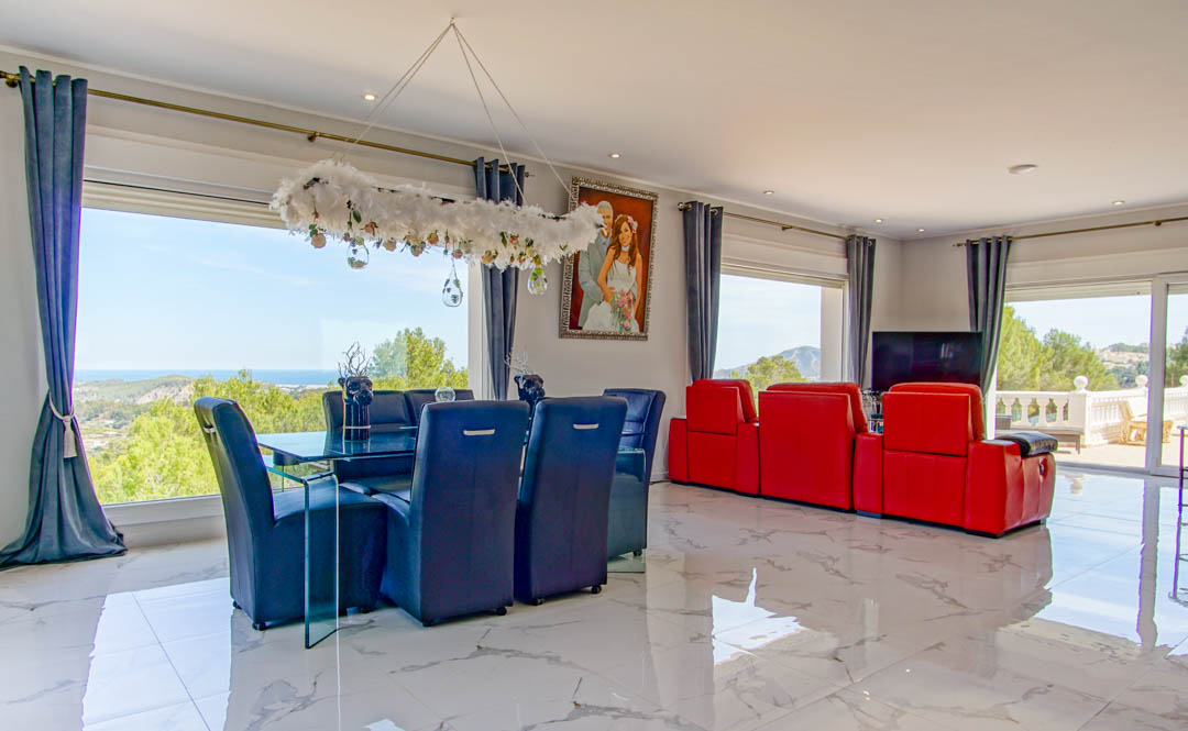 Open-plan living and dining space with polished marble floors, contemporary furniture, and large windows framing panoramic views of the Mediterranean Sea.