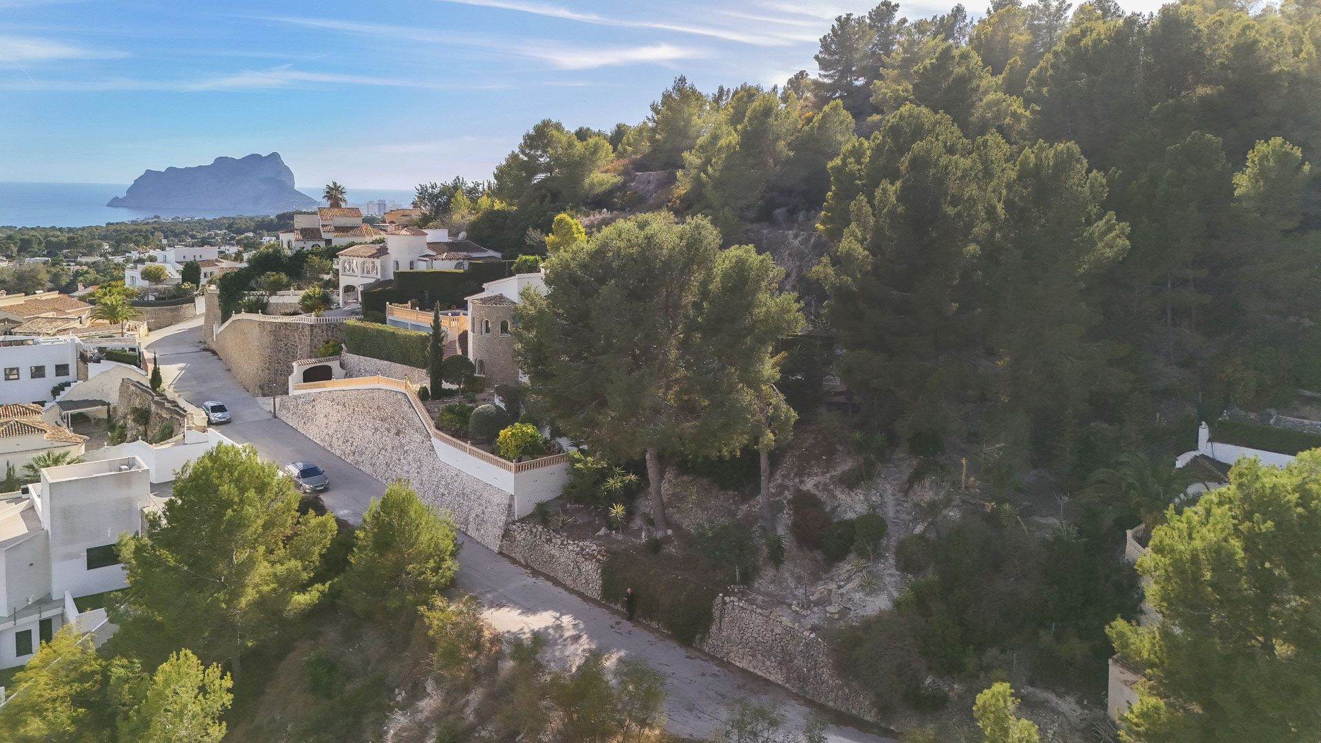 Aerial perspective of the elevated plot in Benissa, showcasing the pine-covered landscape and panoramic sea views toward the Peñón de Ifach.