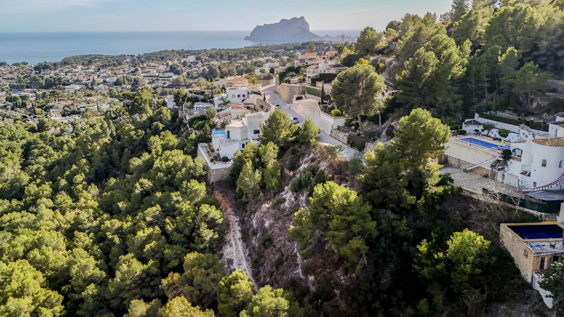Aerial view of the Benissa residential area, highlighting the proximity to the Peñón de Ifach and the extensive protected green zone surrounding the plots.