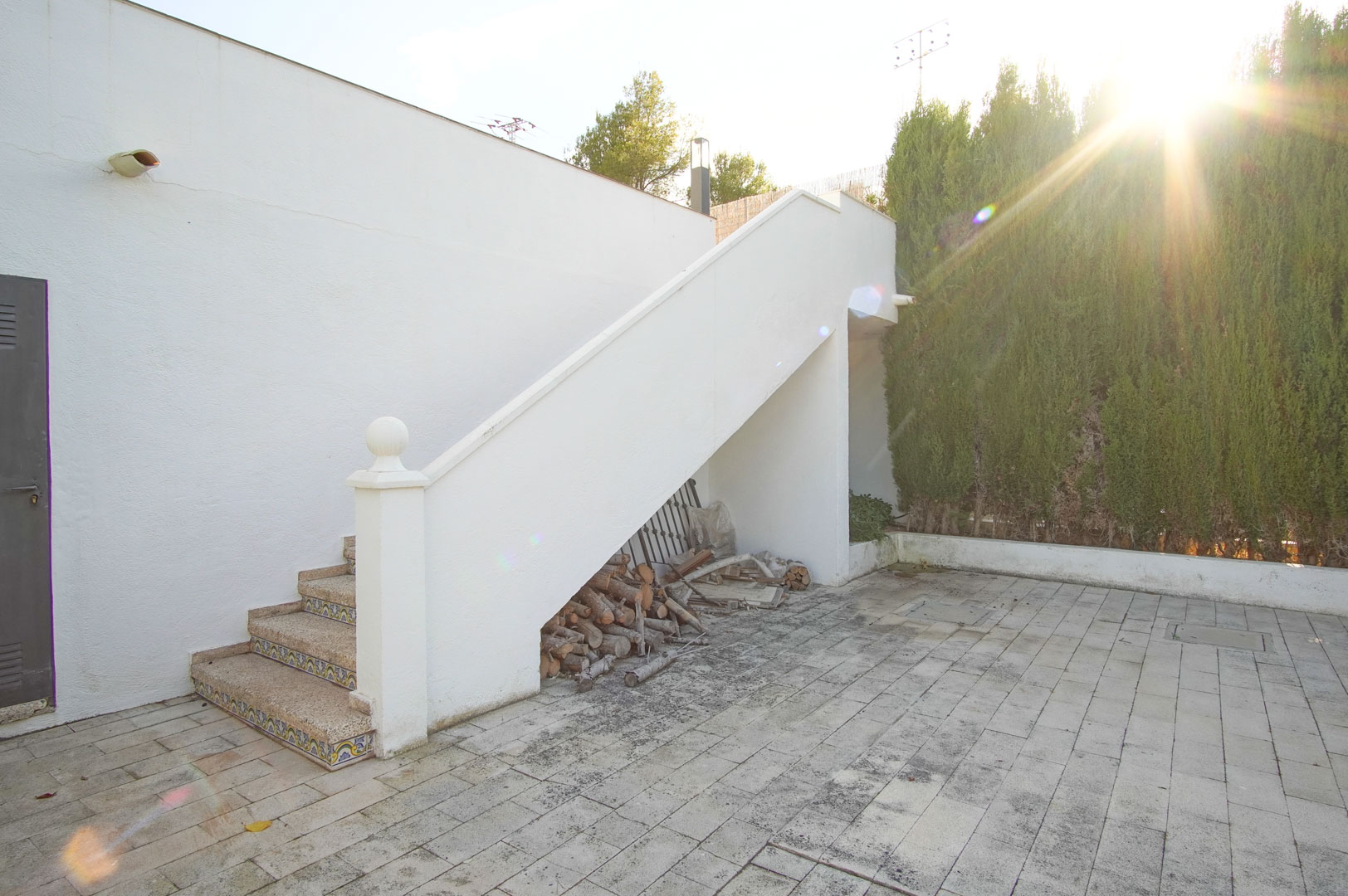 Exterior stone staircase with decorative tile risers leading to the upper level, featuring a paved patio and integrated wood storage space.