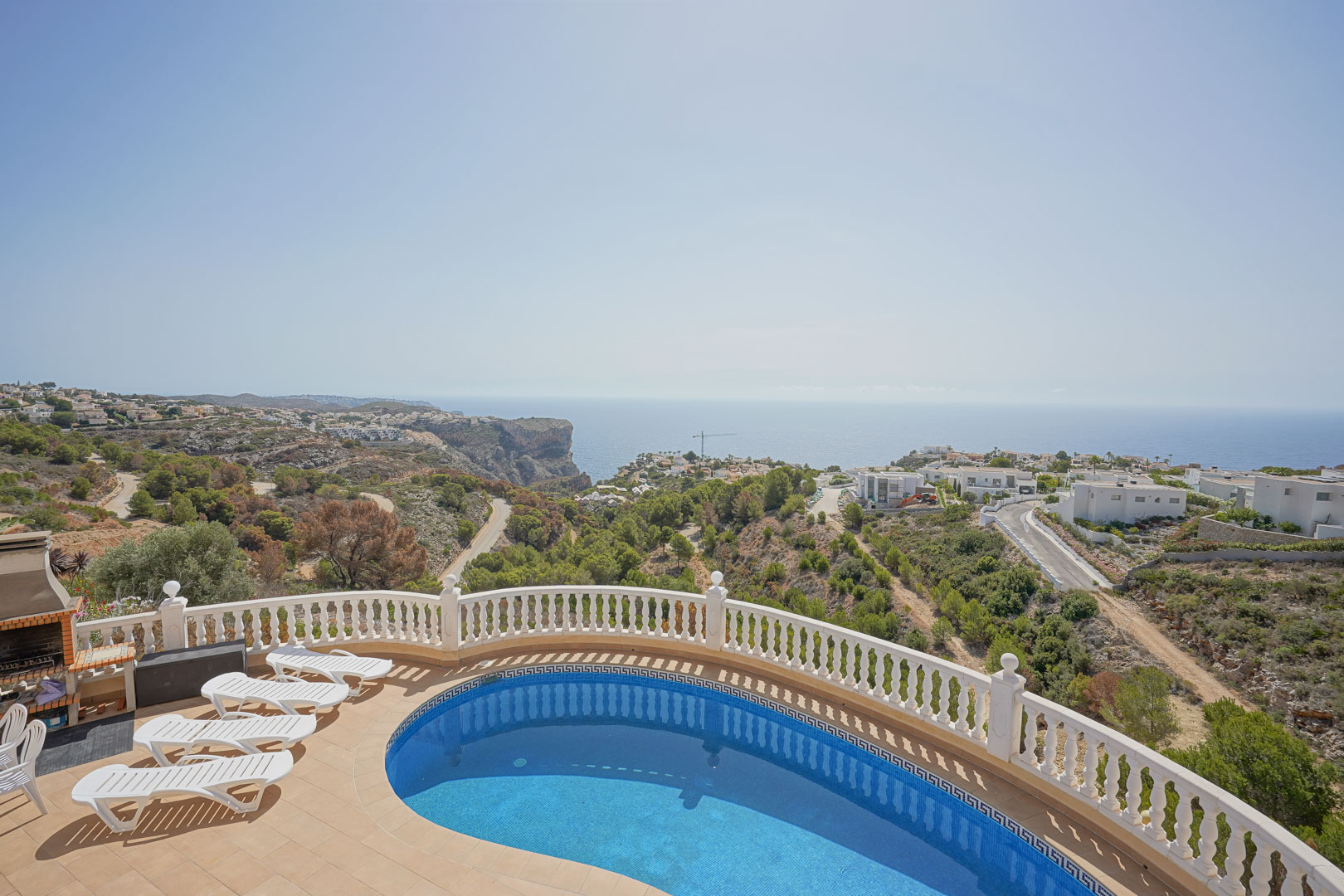 Elevated terrace featuring a kidney-shaped pool, white balustrade, and built-in BBQ, overlooking the Mediterranean Sea and coastal cliffs.