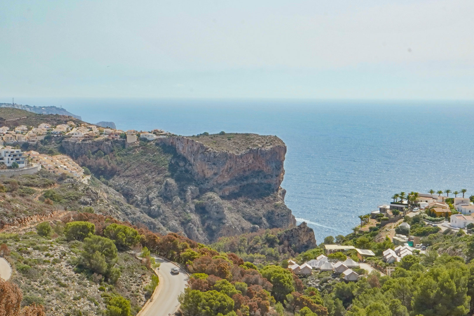 Panoramic view from Cumbre del Sol overlooking the Mediterranean cliffs and sea, featuring the winding coastal road and lush local vegetation.
