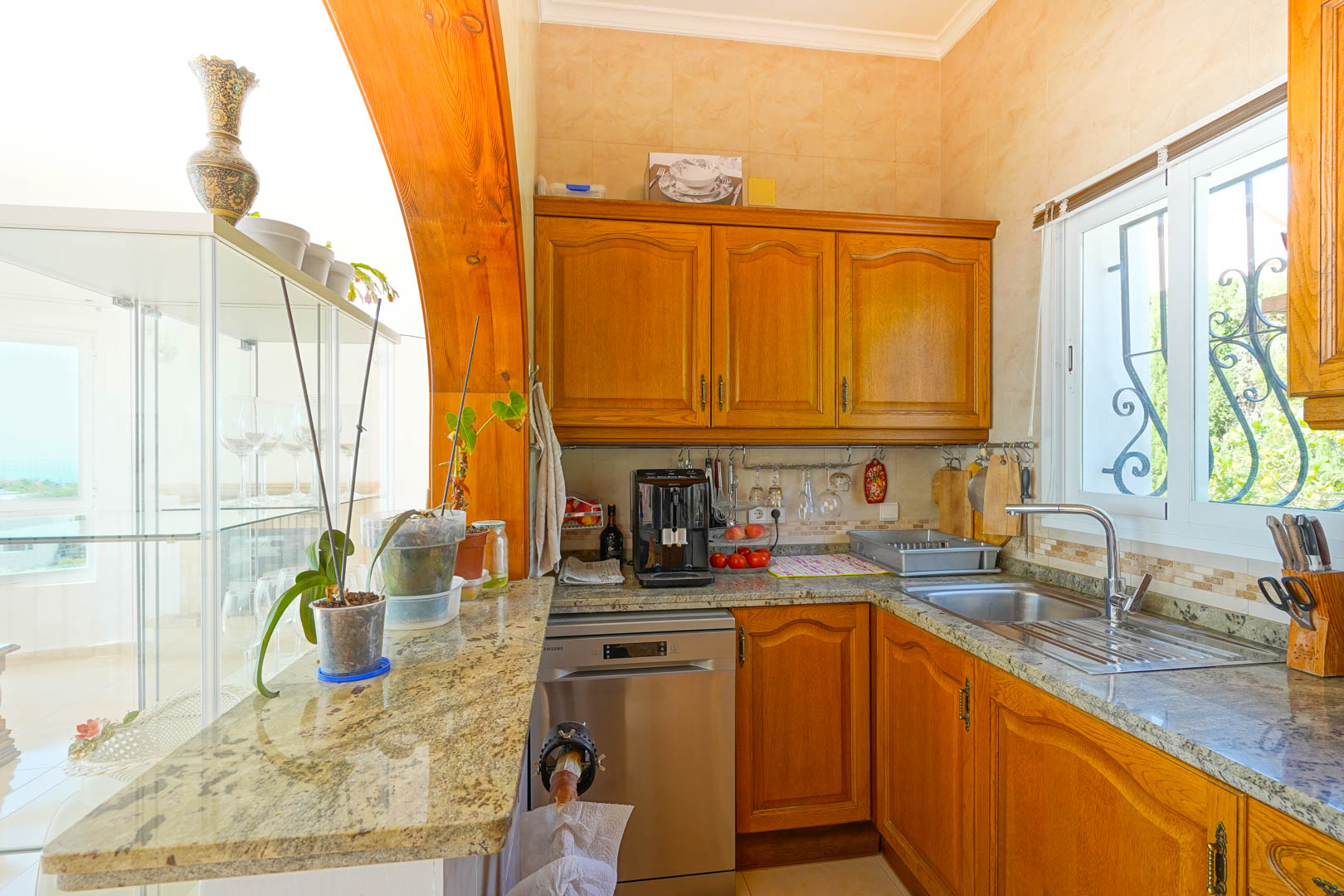 Semi-open kitchen featuring traditional wooden cabinetry, granite countertops, and stainless steel appliances, framed by a prominent solid wood archway.