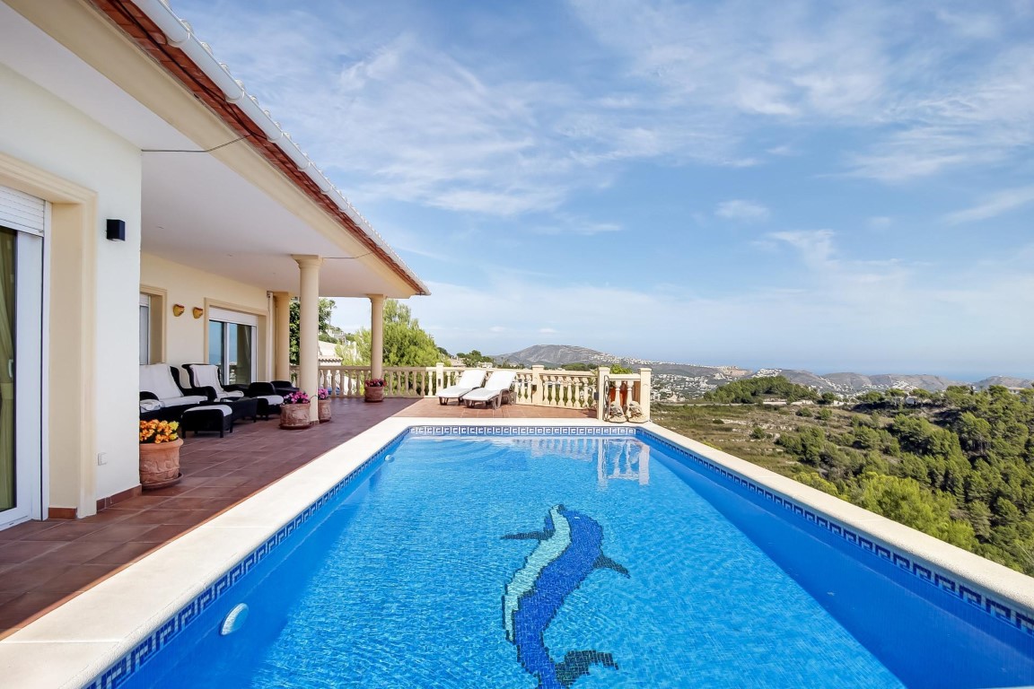 Outdoor swimming pool featuring a dolphin mosaic, surrounded by a terracotta terrace with a covered porch and panoramic Mediterranean Sea views.