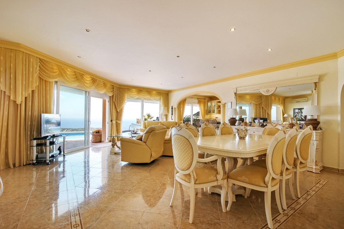 Spacious living and dining area featuring marble floors, classical furniture, and large sliding doors with panoramic Mediterranean Sea views.