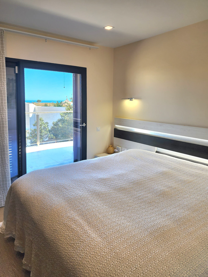 Bright bedroom featuring an integrated LED-lit headboard and direct access to a private terrace with panoramic Mediterranean Sea views.
