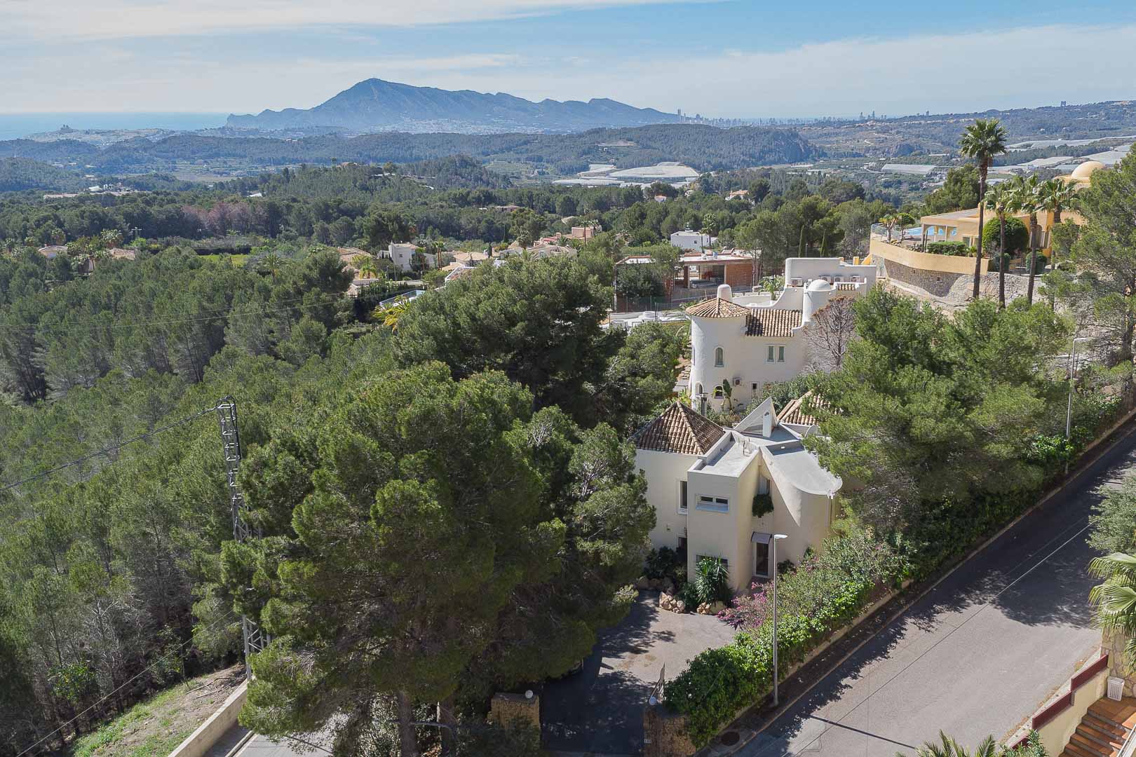 Elevated view of the villa surrounded by lush pine forests, showcasing its traditional Mediterranean design and expansive views of the sea and mountains.