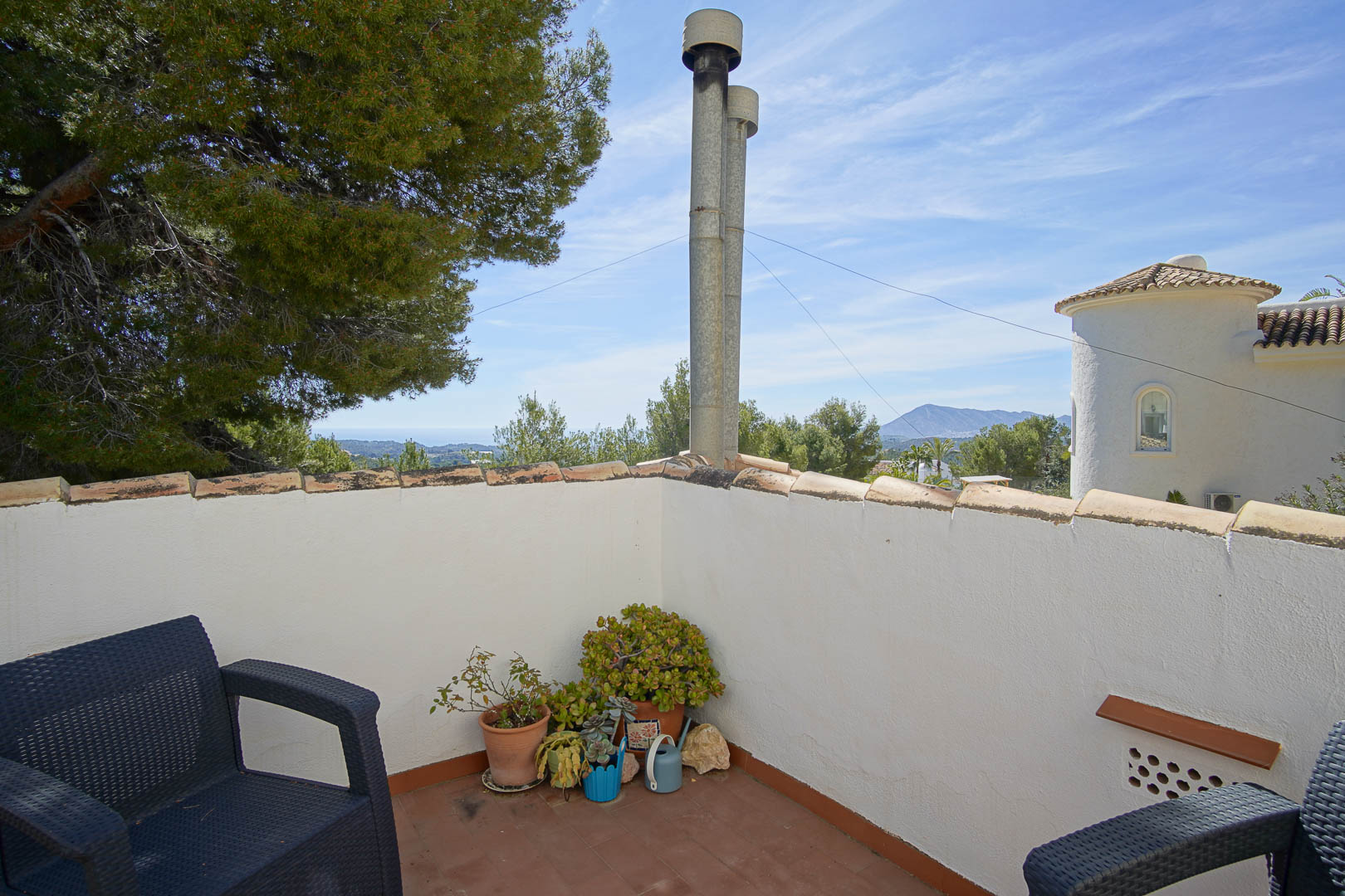 Upper-level terrace featuring terracotta tiling, outdoor seating, and panoramic views of the Mediterranean Sea and surrounding mountains.