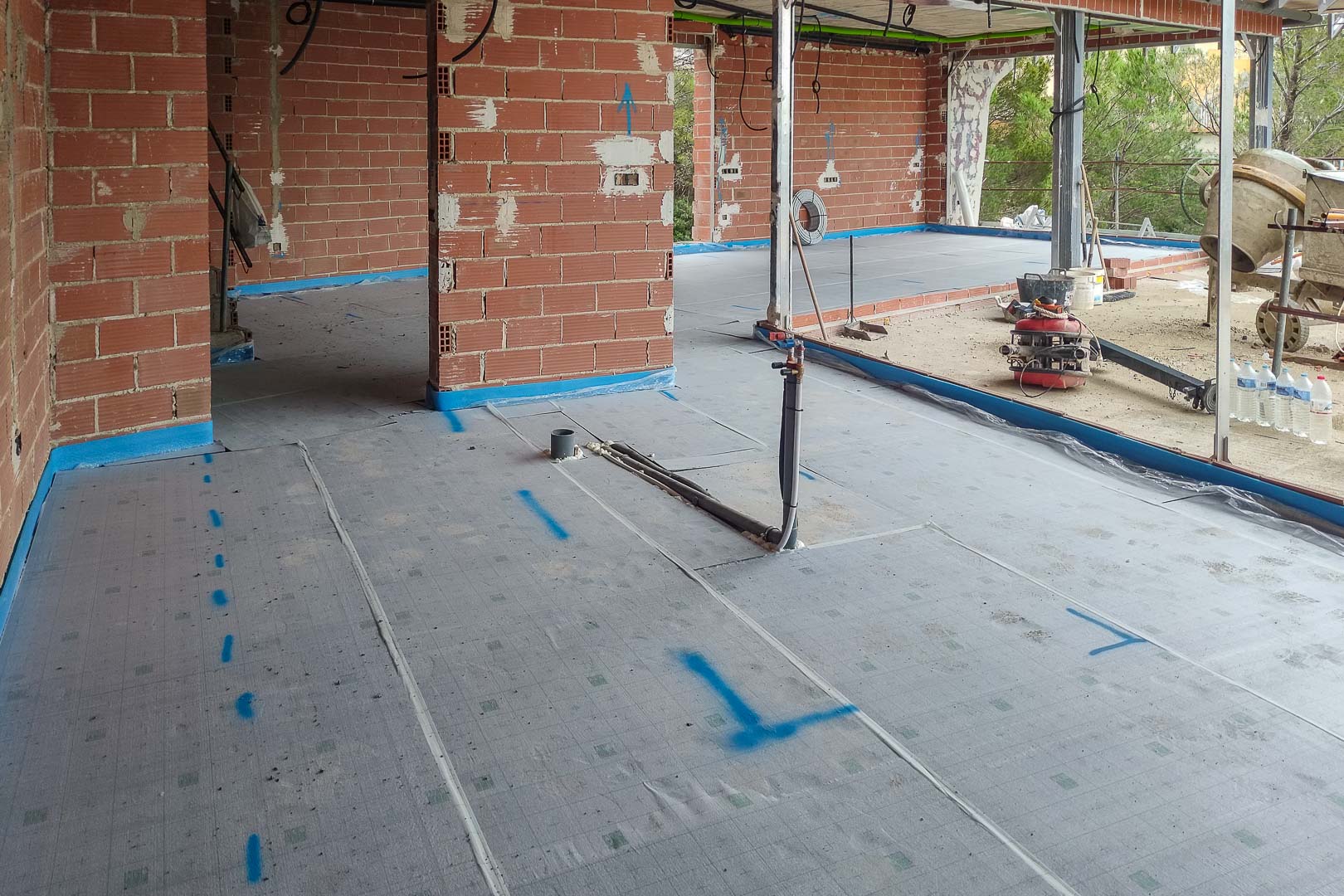 Construction progress showing floor insulation membrane and plumbing rough-ins, prepared for the installation of underfloor heating systems.