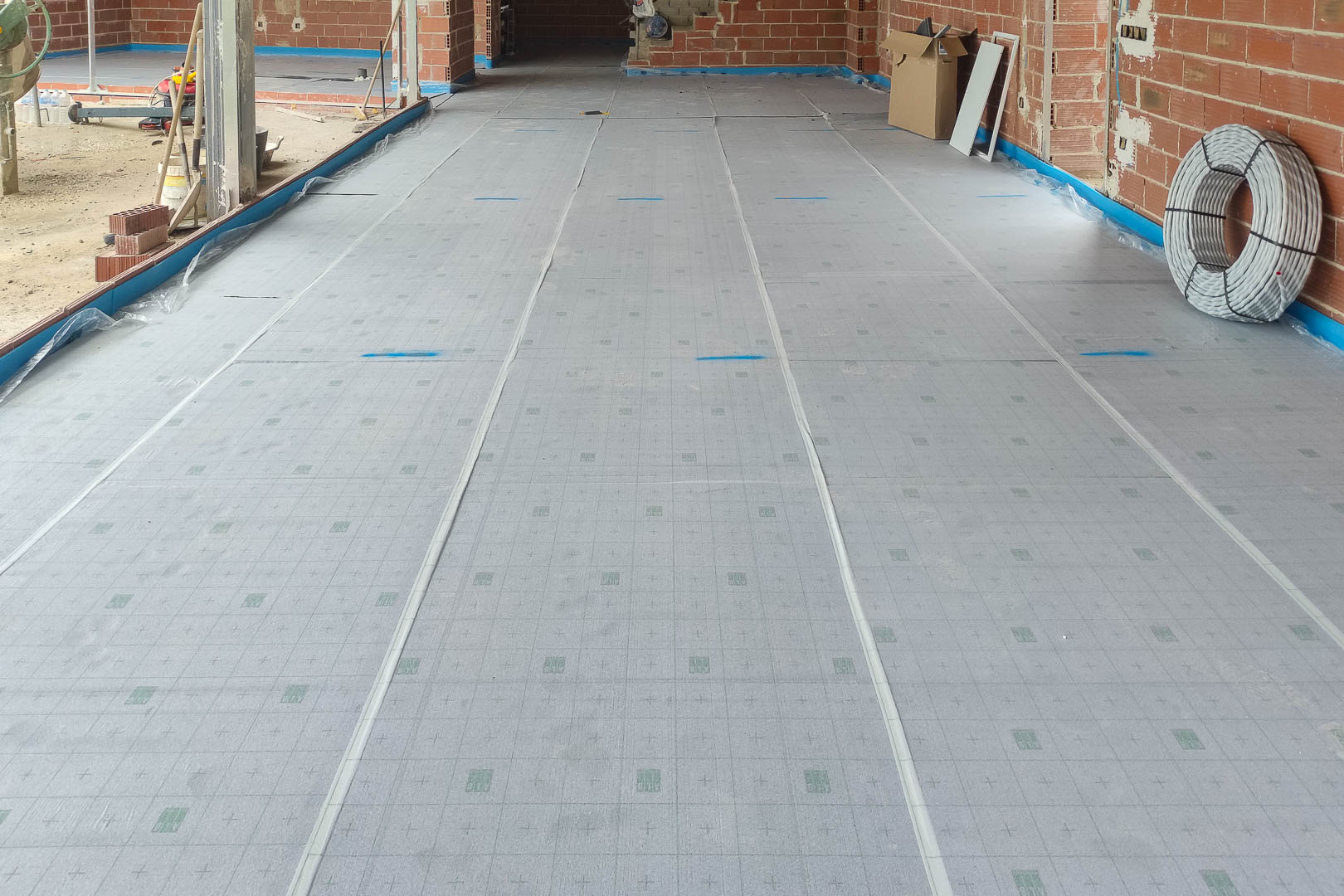 Installation of thermal insulation panels for the underfloor heating system, showcasing the technical preparation and high-efficiency materials used.