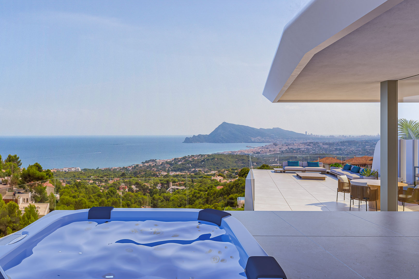 Main terrace featuring an outdoor spa and panoramic views of Altea bay. Includes a lounge area with designer furniture and glass railings for unobstructed coastal visibility.