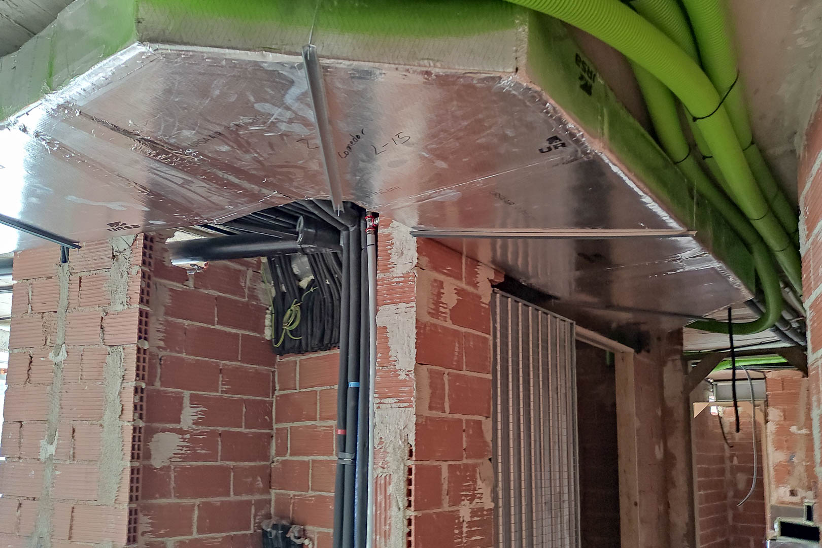 Technical view of the aerothermal climate control installation, featuring insulated ductwork and high-efficiency piping integrated into the brickwork.