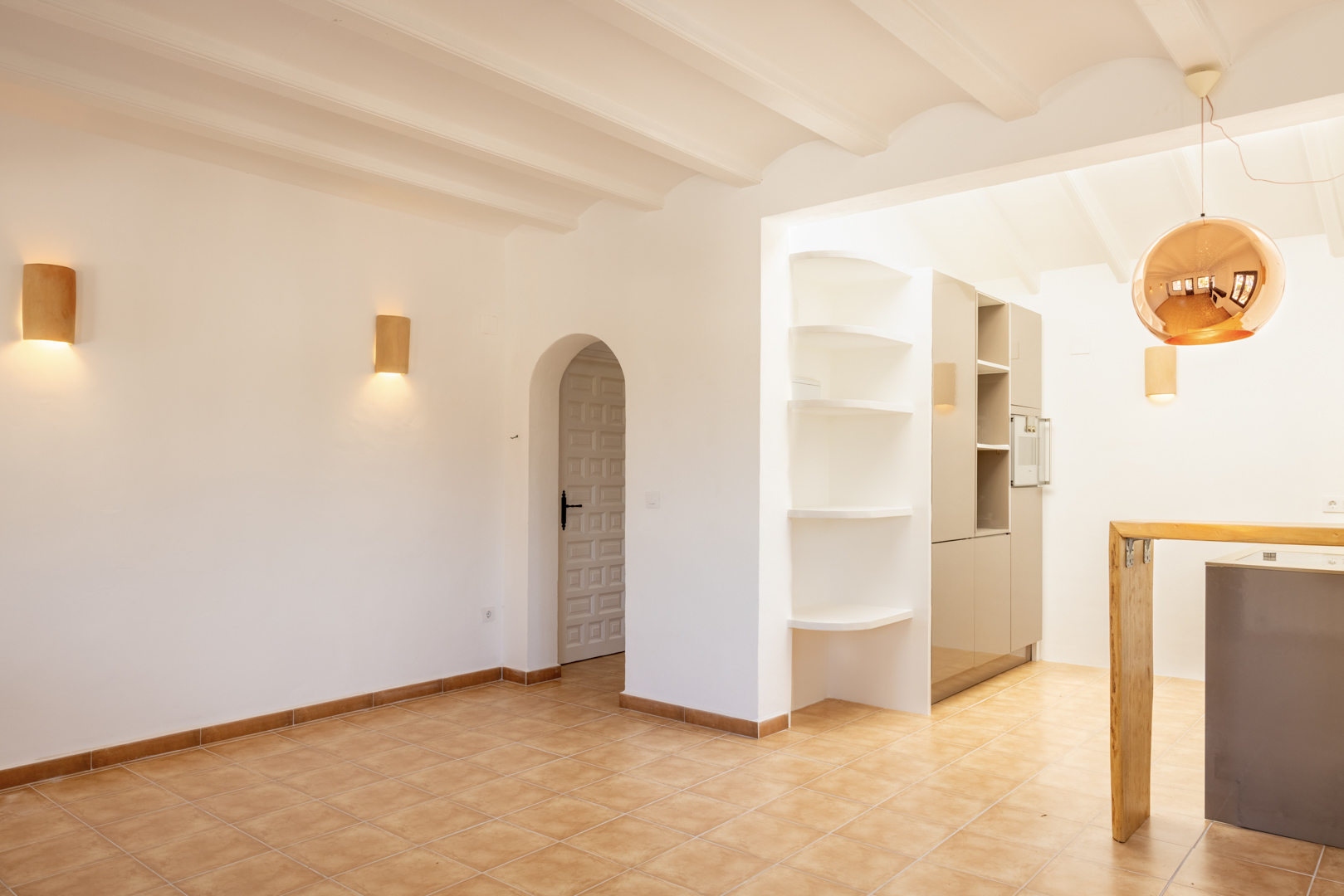 Bright interior featuring white shelving and an open kitchen. A copper spherical pendant lamp hangs above.
