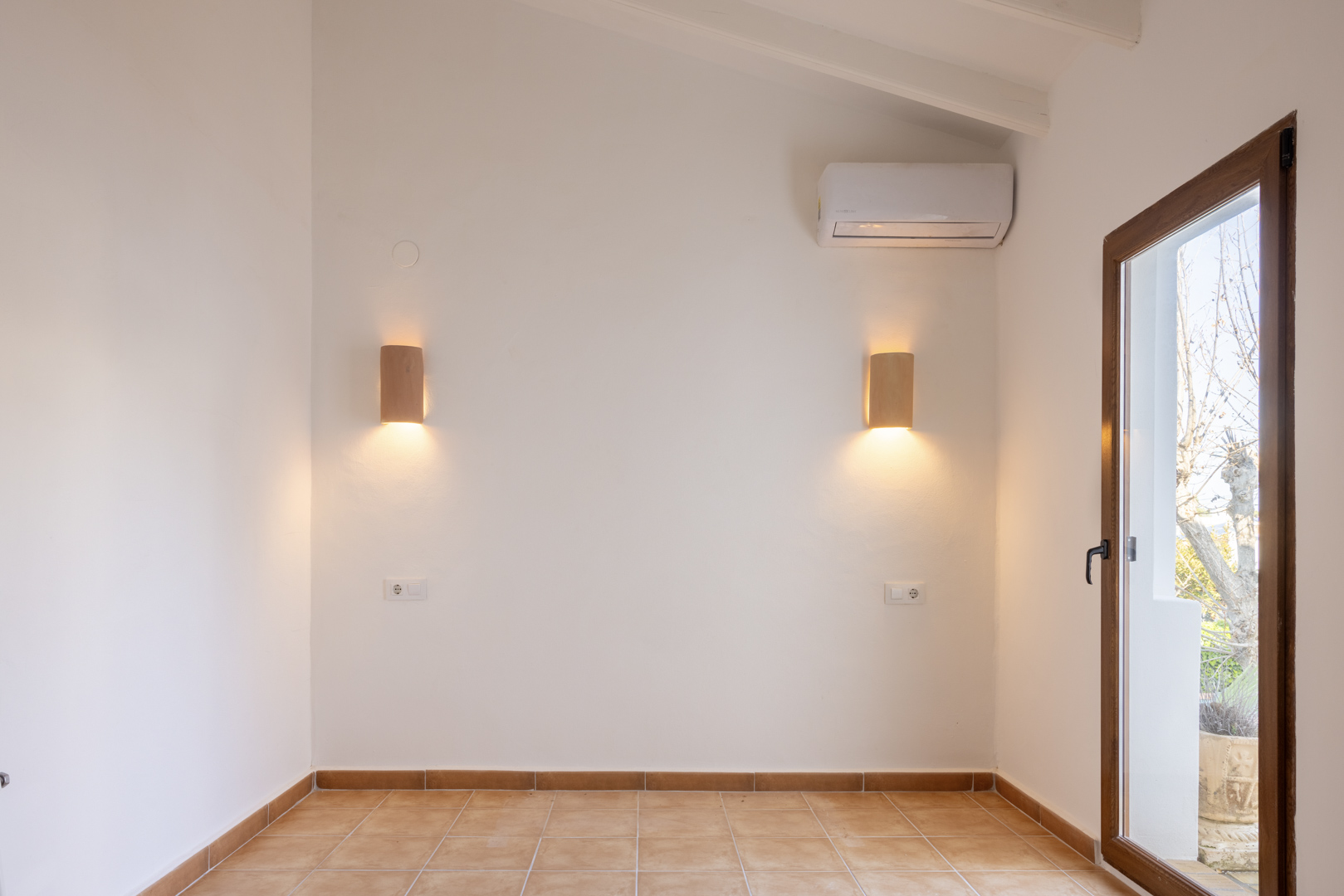 Bright room featuring wood sconces and tiled flooring, with outdoor access.